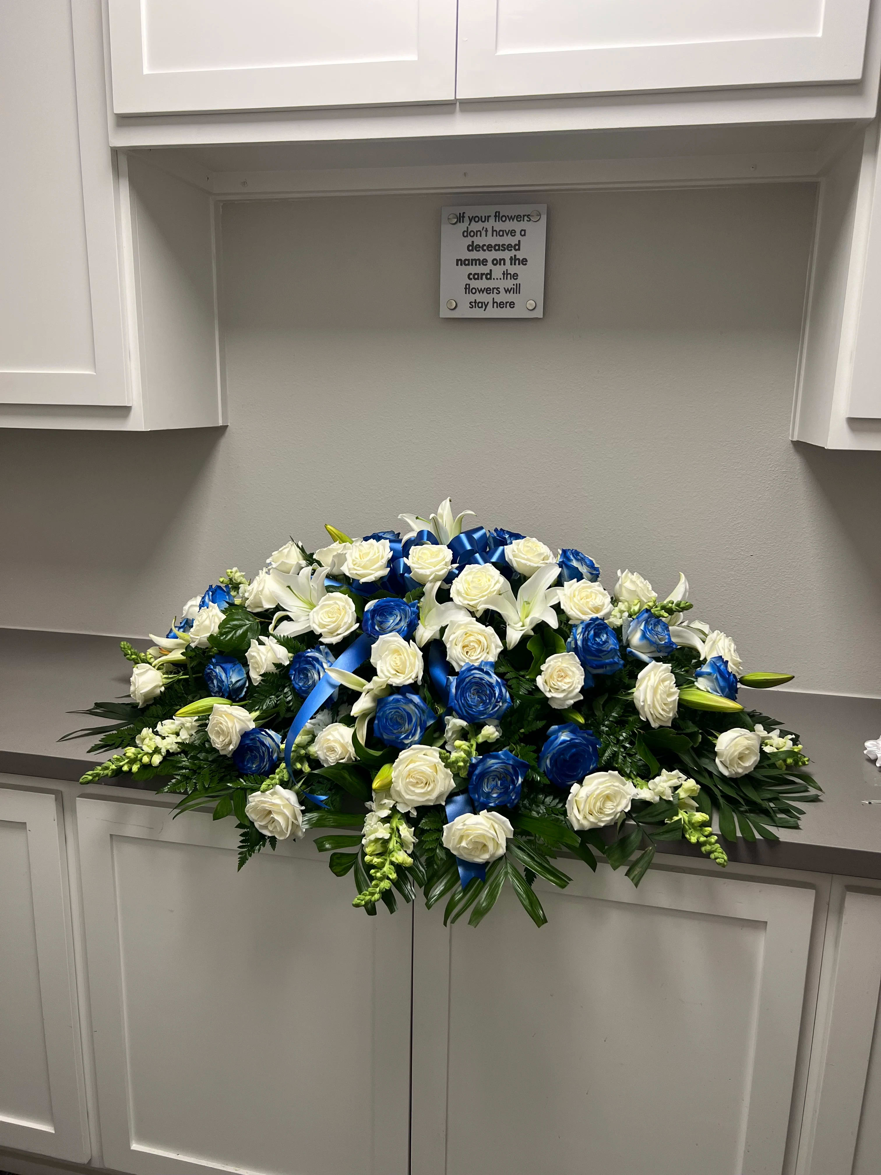 Large white and blue rose funeral spray with ribbon