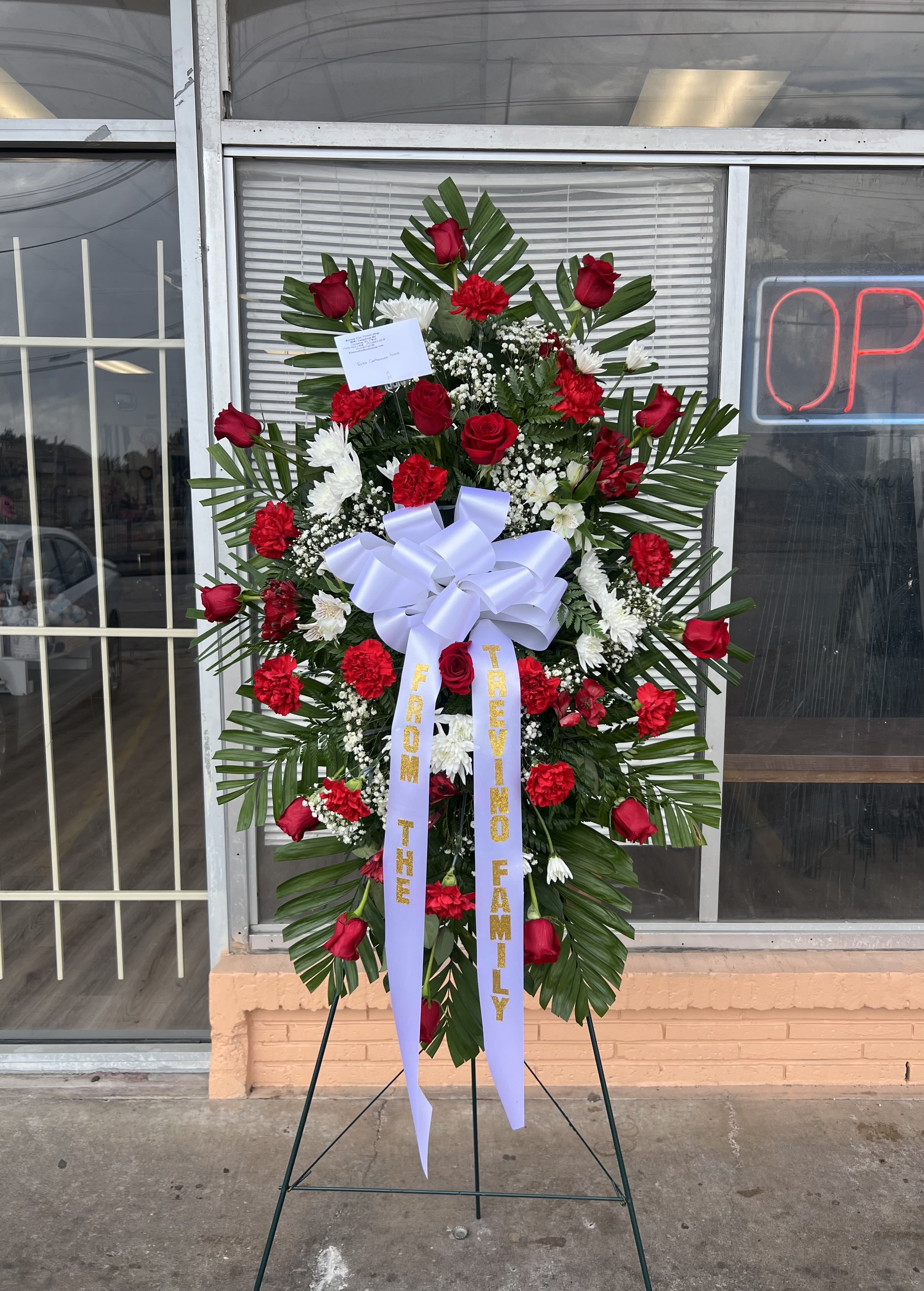 Standing floral wreath with red roses and white flowers on an easel