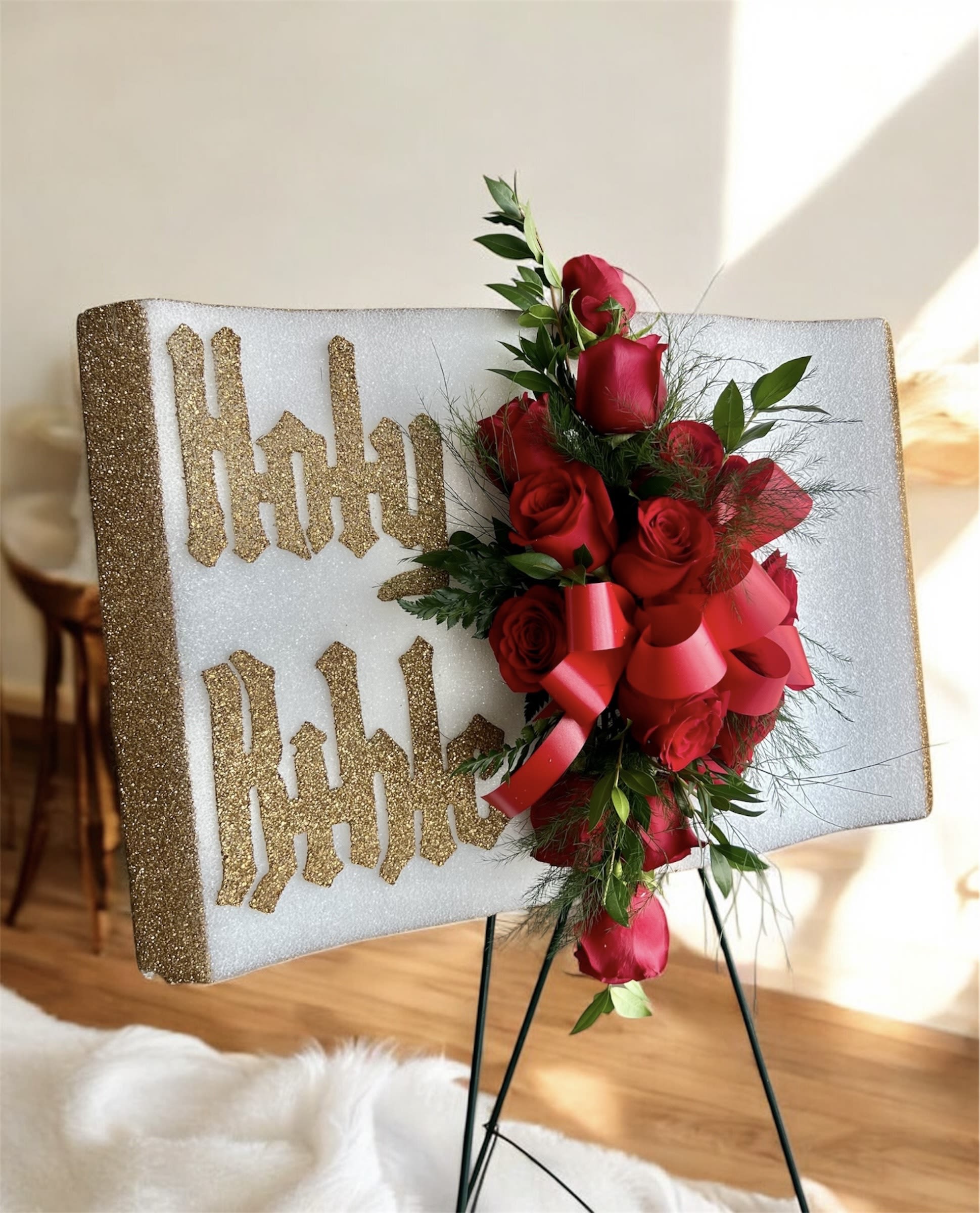 Red rose arrangement on a glittery display board with gold lettering