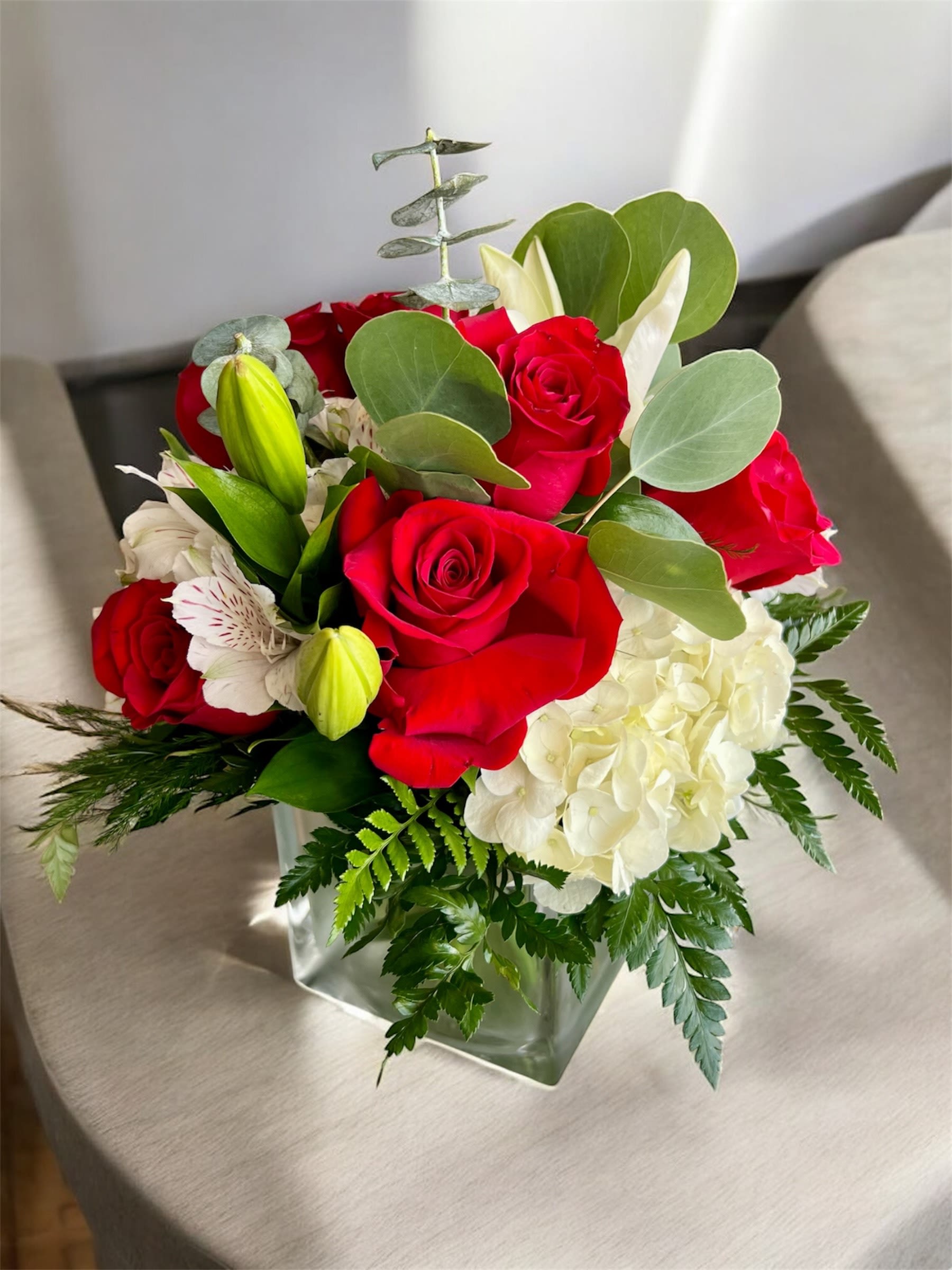 Red roses and white hydrangea in a square glass vase
