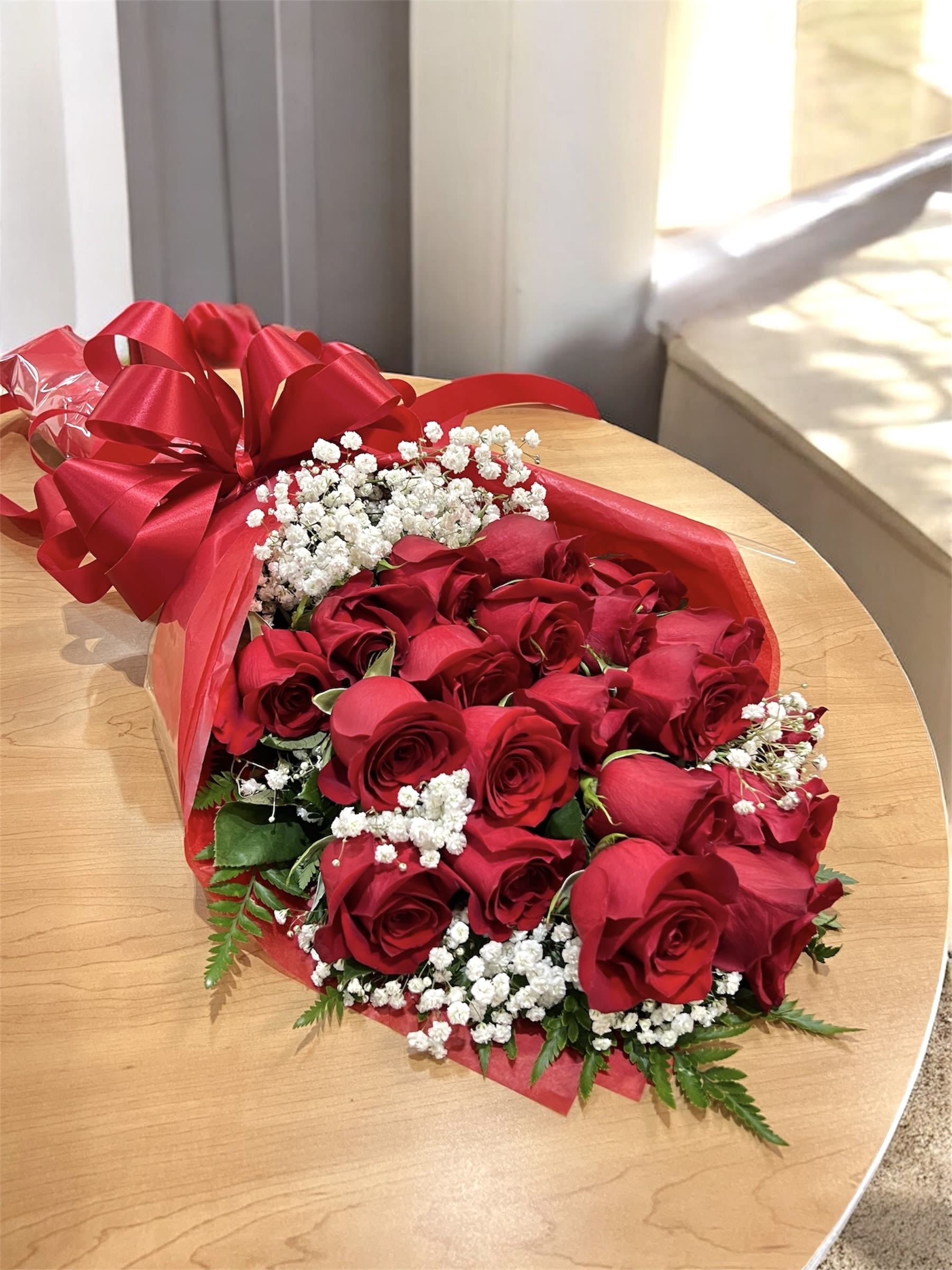 Bouquet of red roses with white baby's breath wrapped in red paper