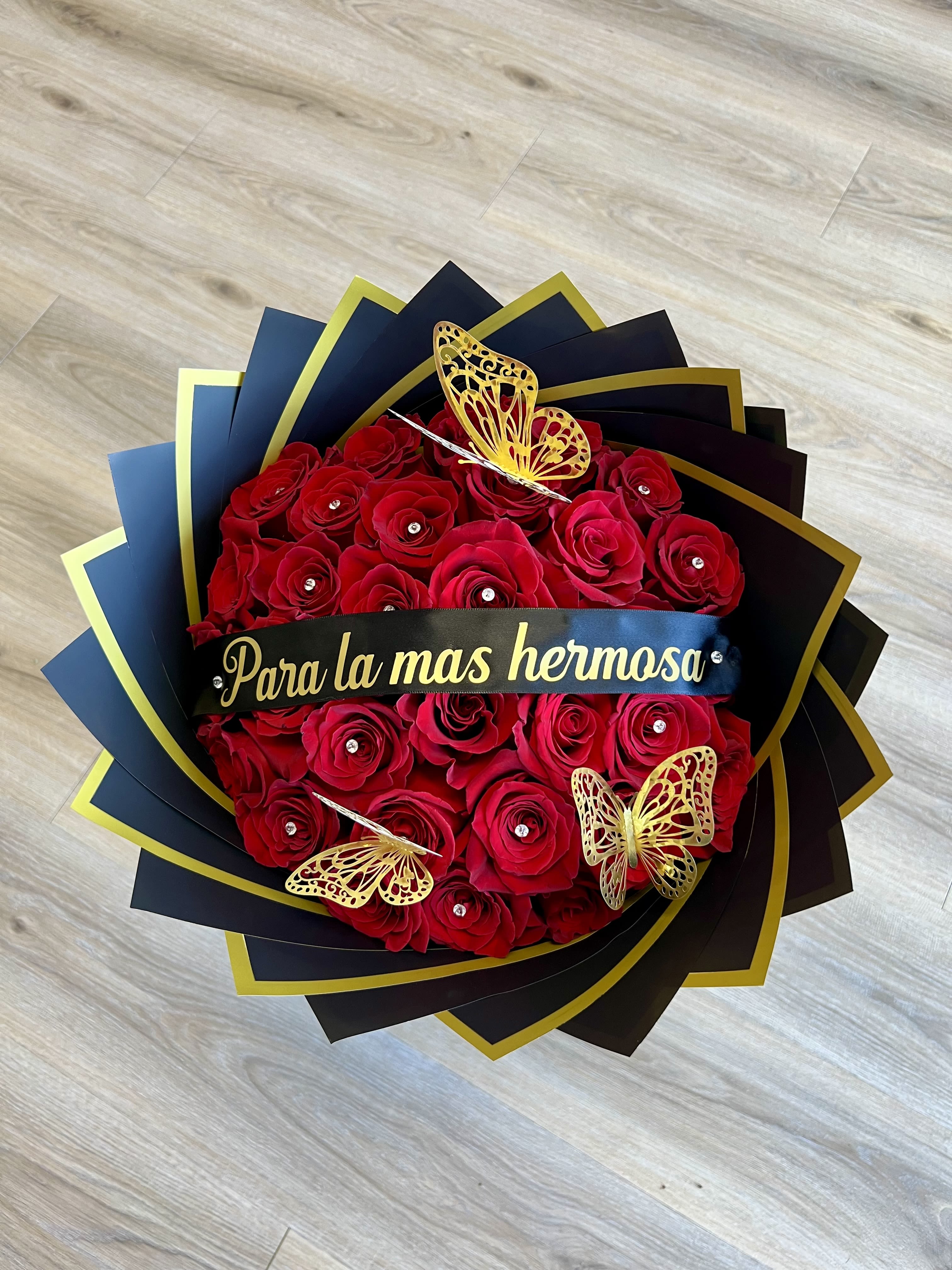 Red rose bouquet with gold butterfly decorations and a black ribbon