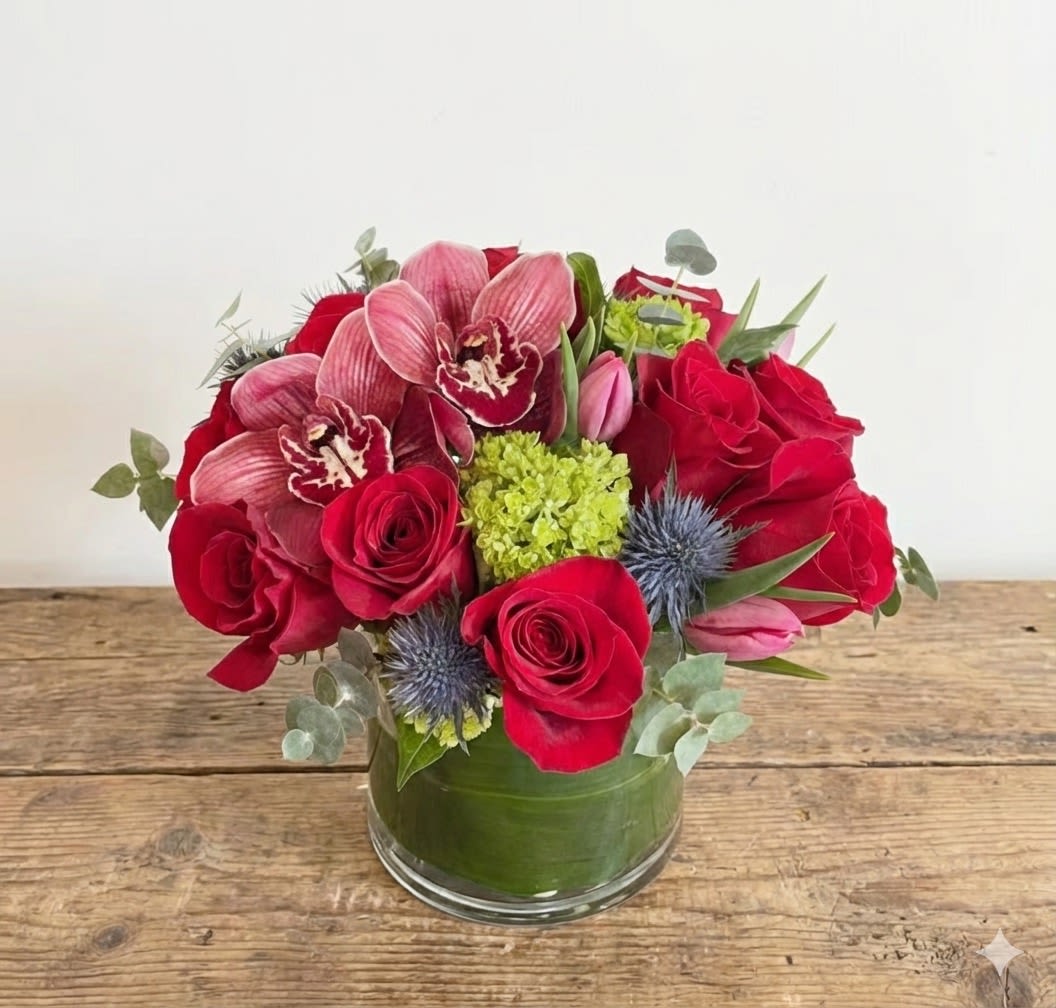 Red roses and pink orchids arranged in a glass vase