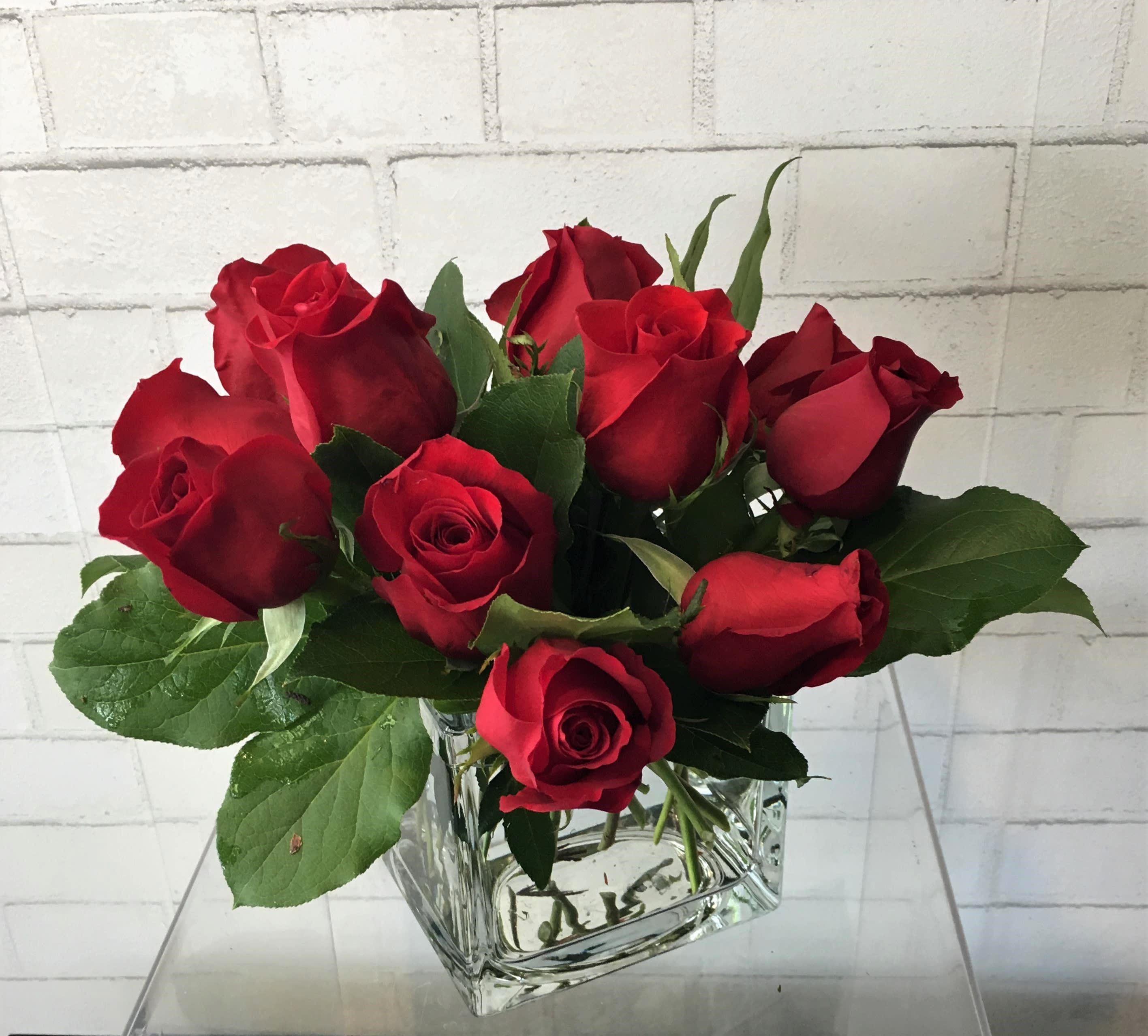 Red roses arranged in a clear square glass vase