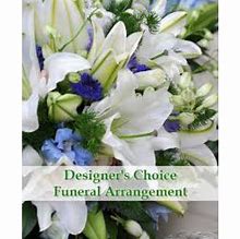 White lilies and blue flowers in a funeral arrangement