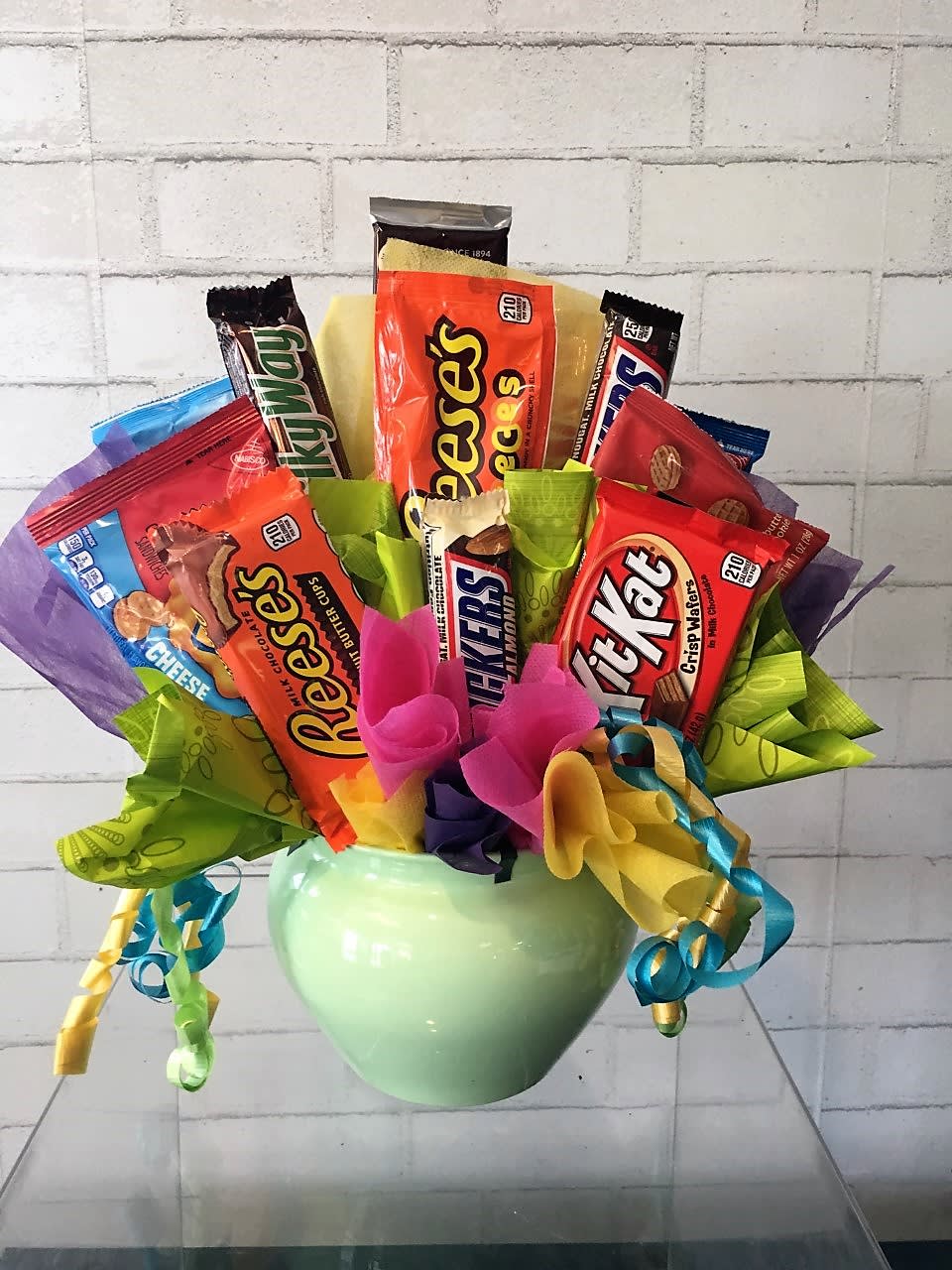 Candy bouquet in a green vase with assorted chocolate bars and ribbons