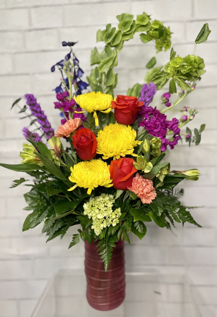 Colorful mixed flower arrangement in a tall burgundy vase