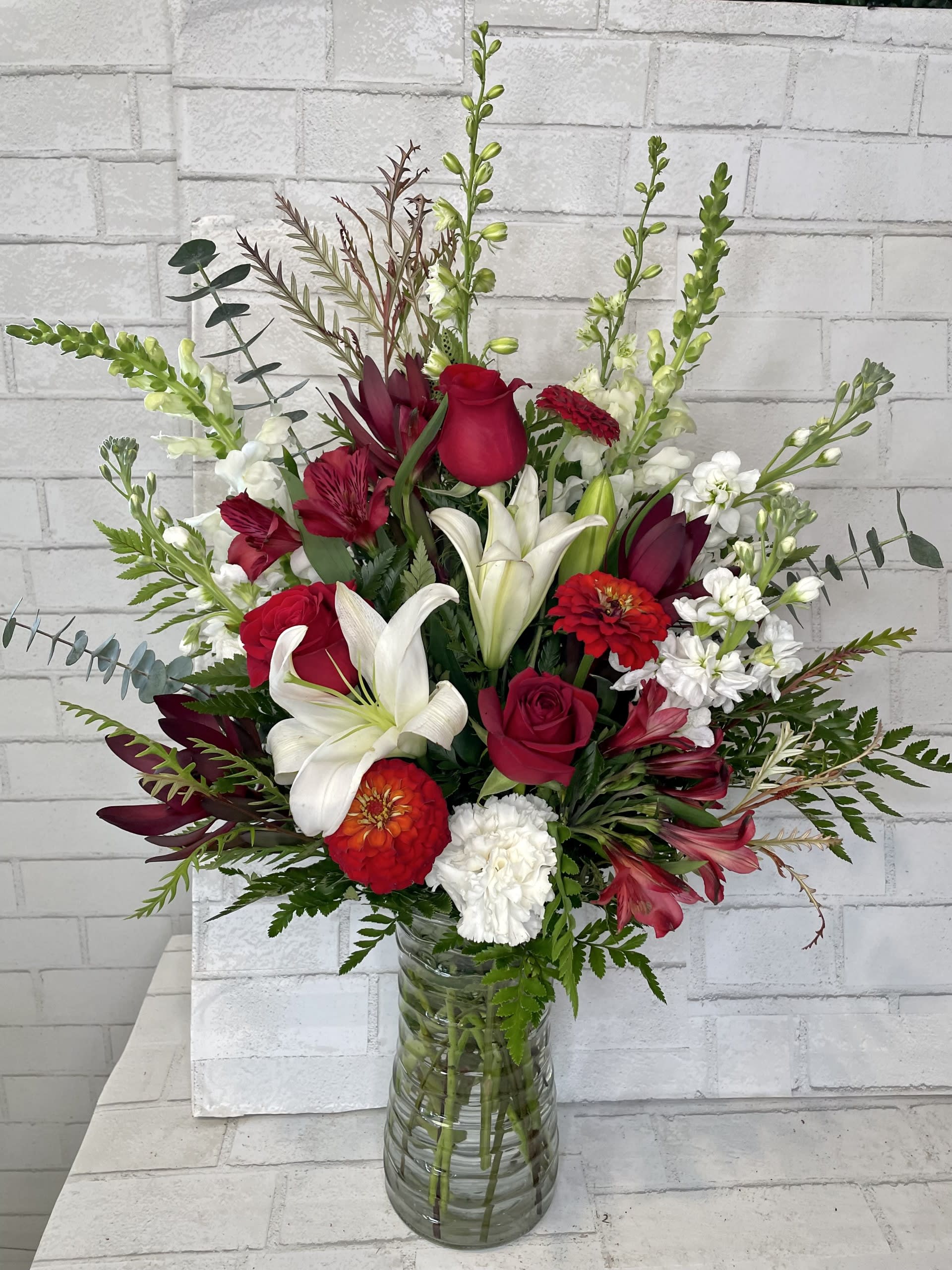 Red and white mixed flower arrangement in a glass vase