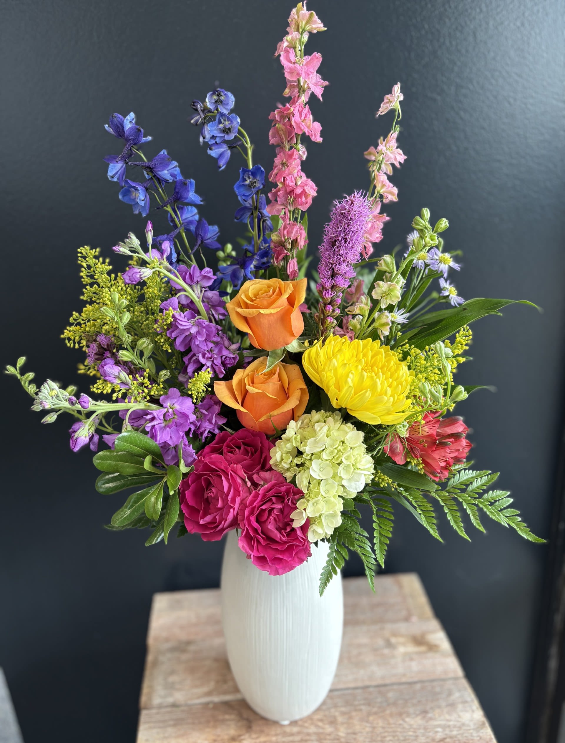 Colorful mixed bouquet in a white vase with roses and tall blooms