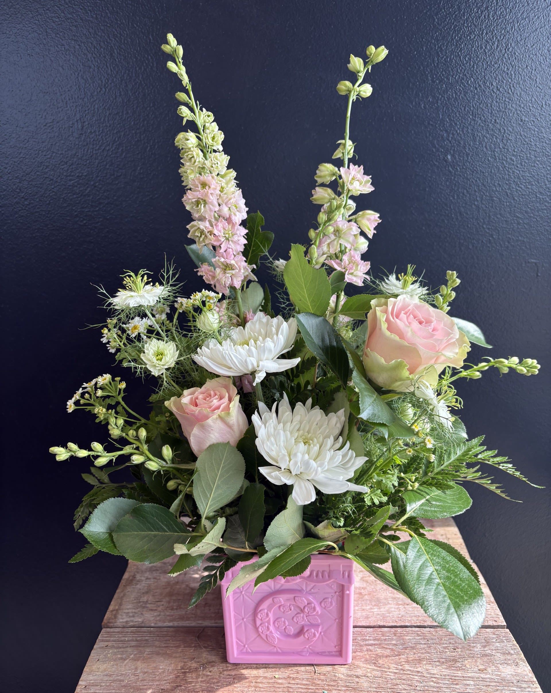 Bundle of Joy  - This charming baby arrangement features soft, cheerful blooms nestled inside a classic ABC block container, symbolizing the joy of new beginnings. Gentle colors and playful details create a sweet, welcoming display perfect for celebrating a new arrival. Let us know boy or girl!