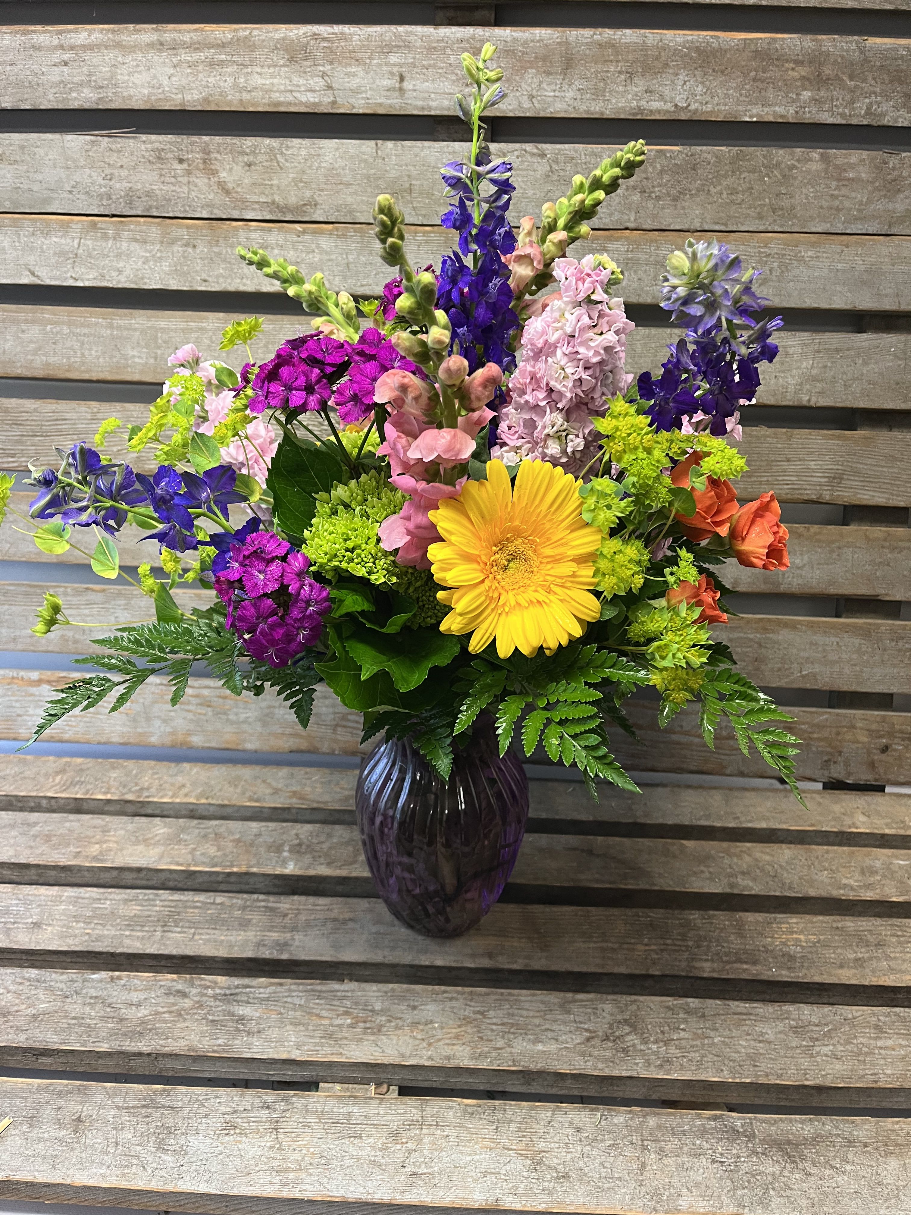 Colorful mixed flower arrangement in a dark glass vase