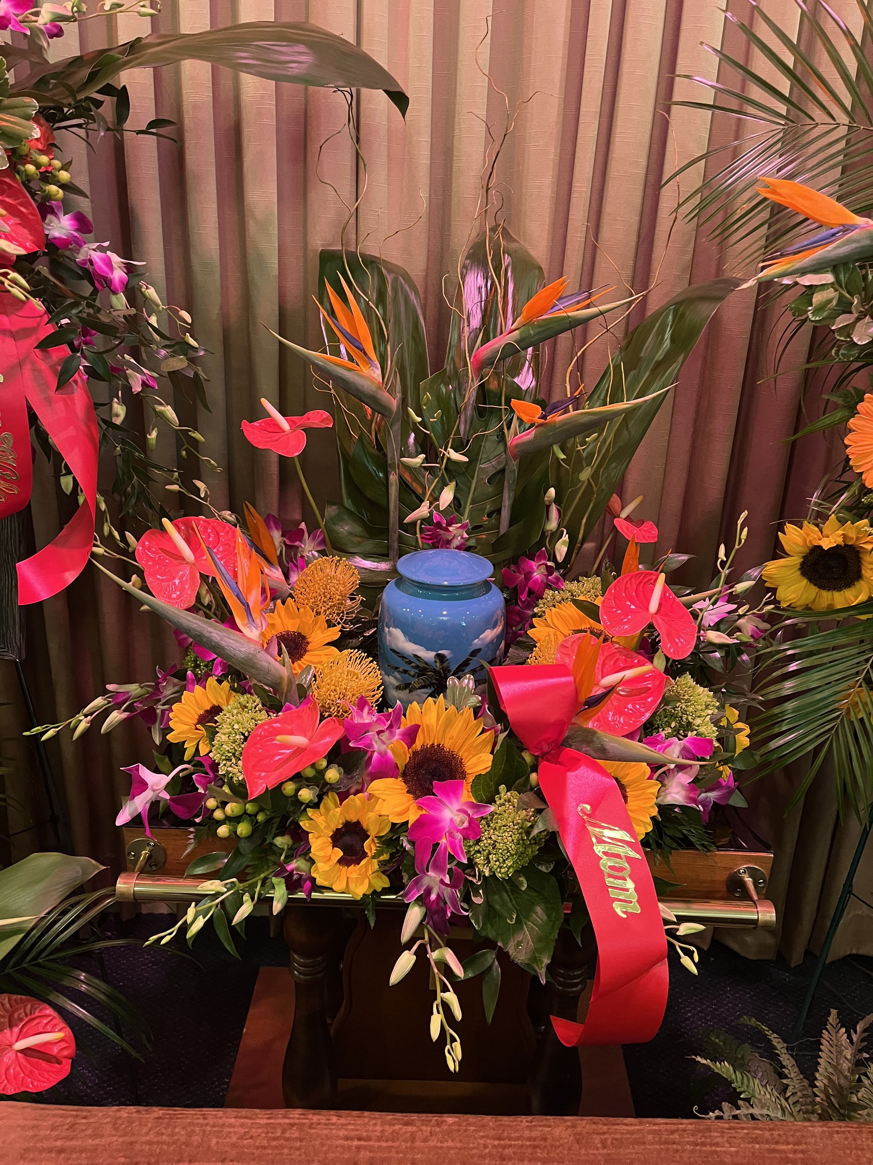 Large tropical floral arrangement with sunflowers, orchids, and an urn centerpiece
