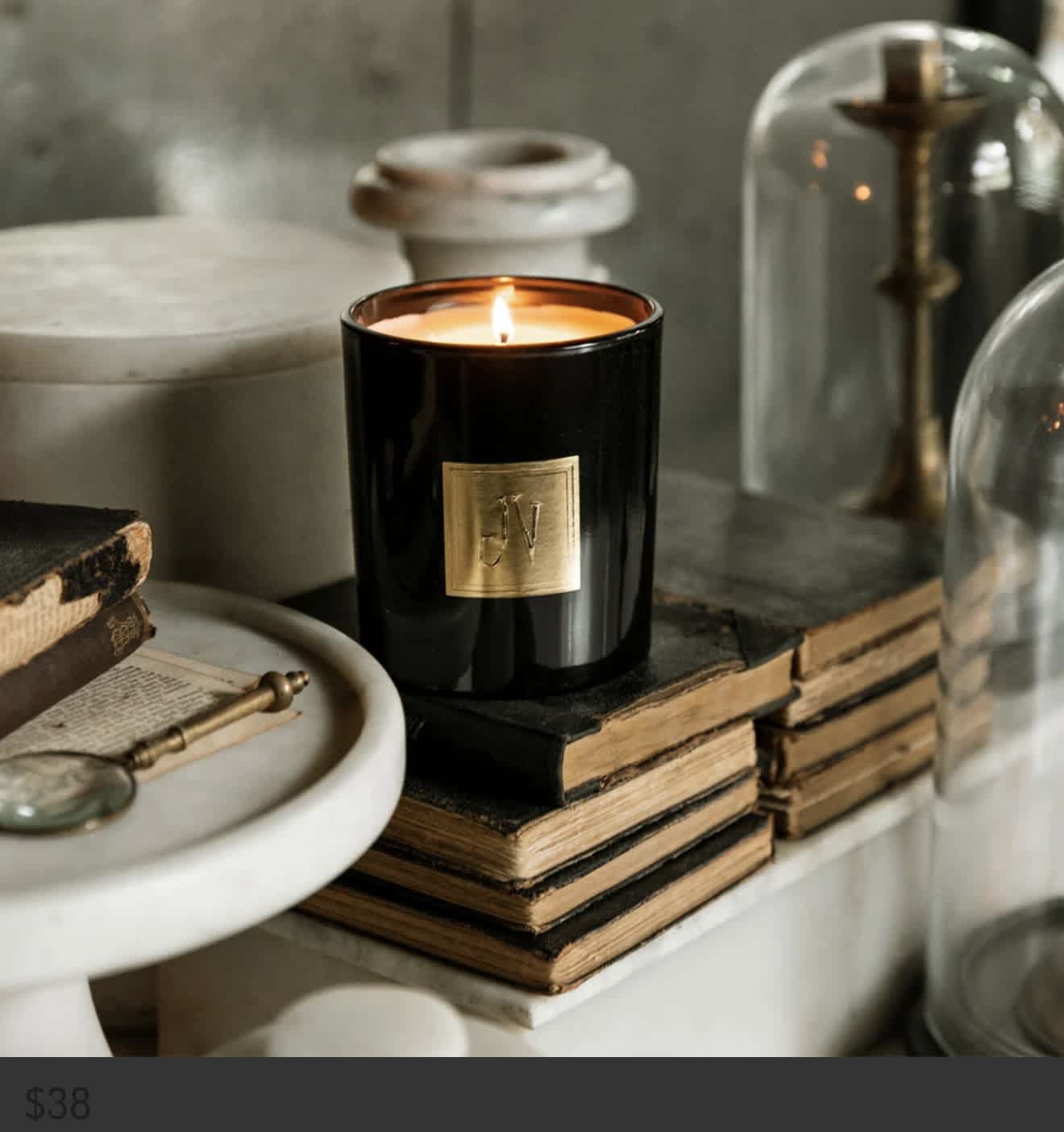 Lit black candle in a glass jar on stacked books