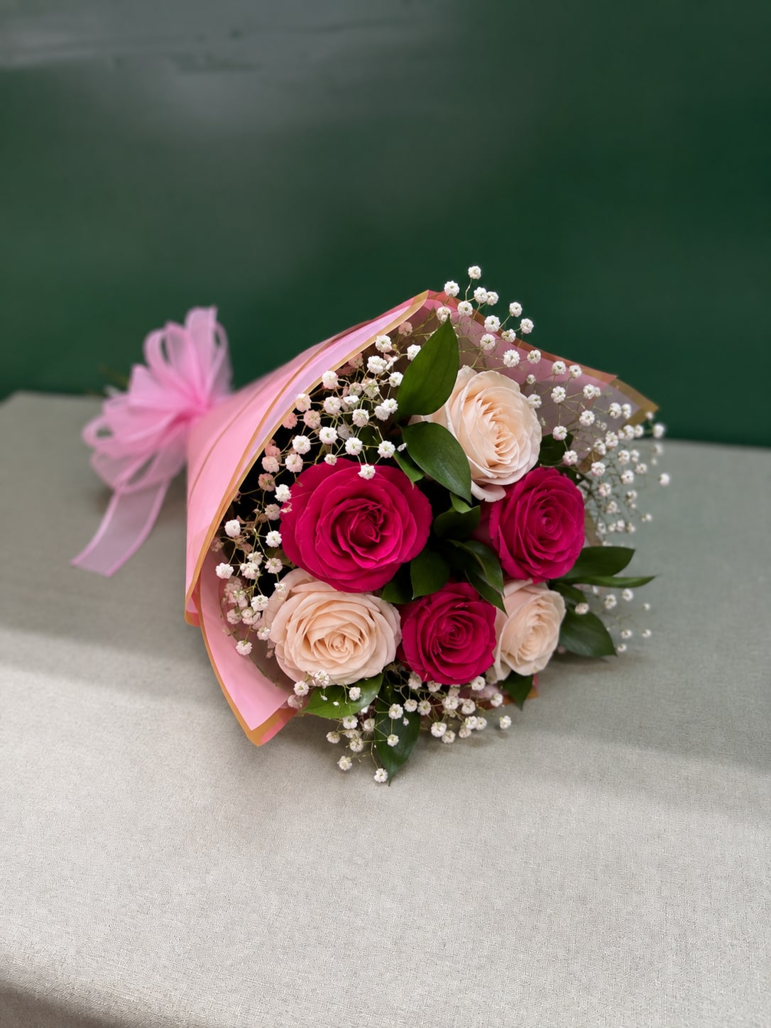Bouquet of pink and blush roses with baby's breath wrapped in pink paper