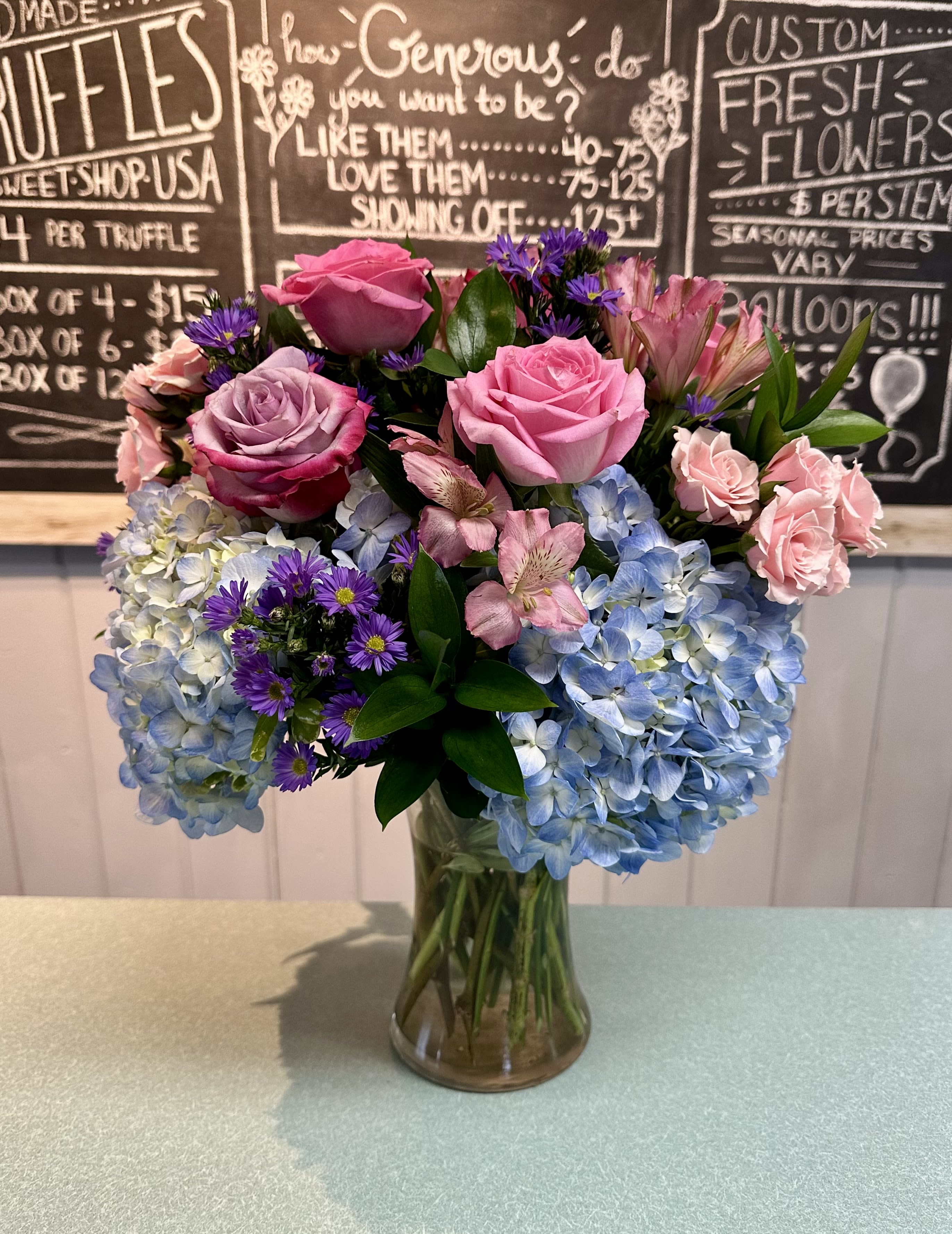 Pink roses and blue hydrangeas arranged in a glass vase