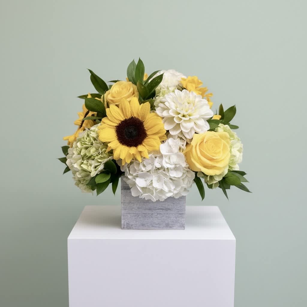 Yellow and white flower arrangement in a gray square vase