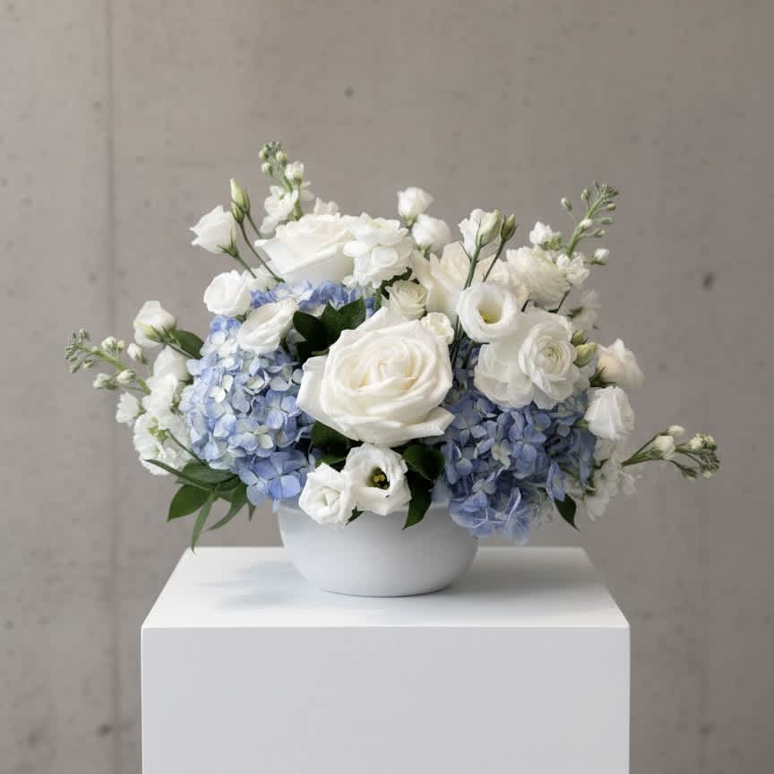 White and pale blue floral arrangement in a white bowl vase