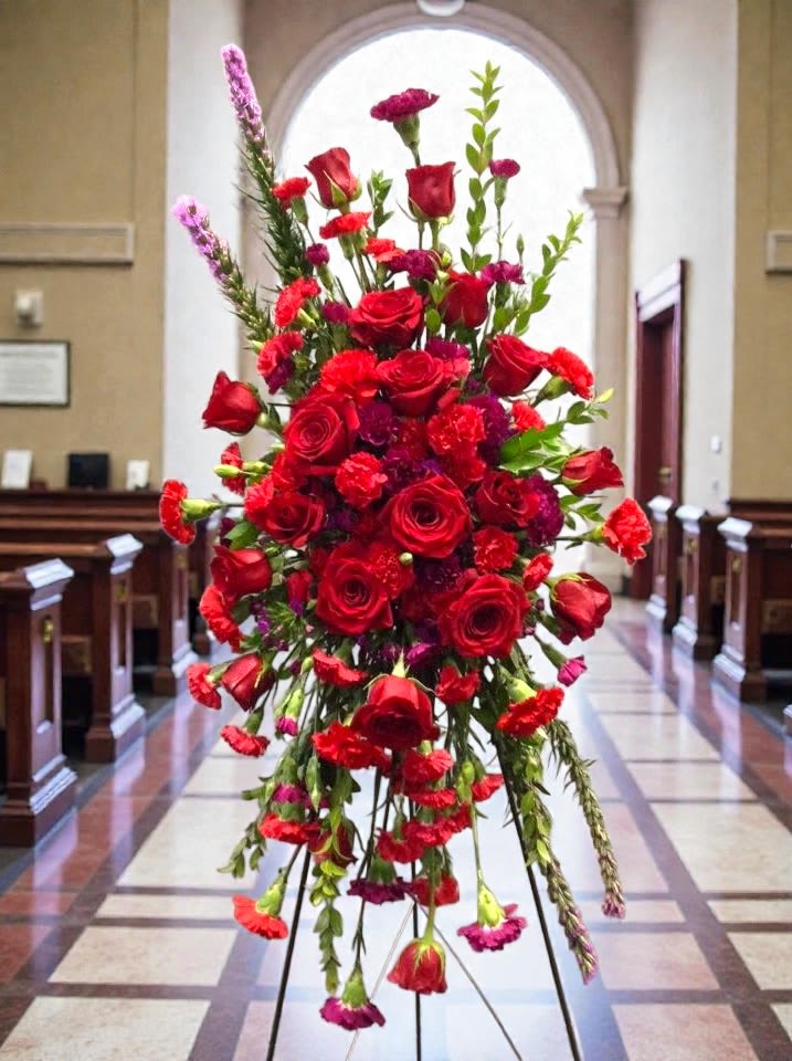 Compassion Easel Spray - Rich red roses and carnations with purple accents convey deep compassion and love for a bold, reverent tribute. 
