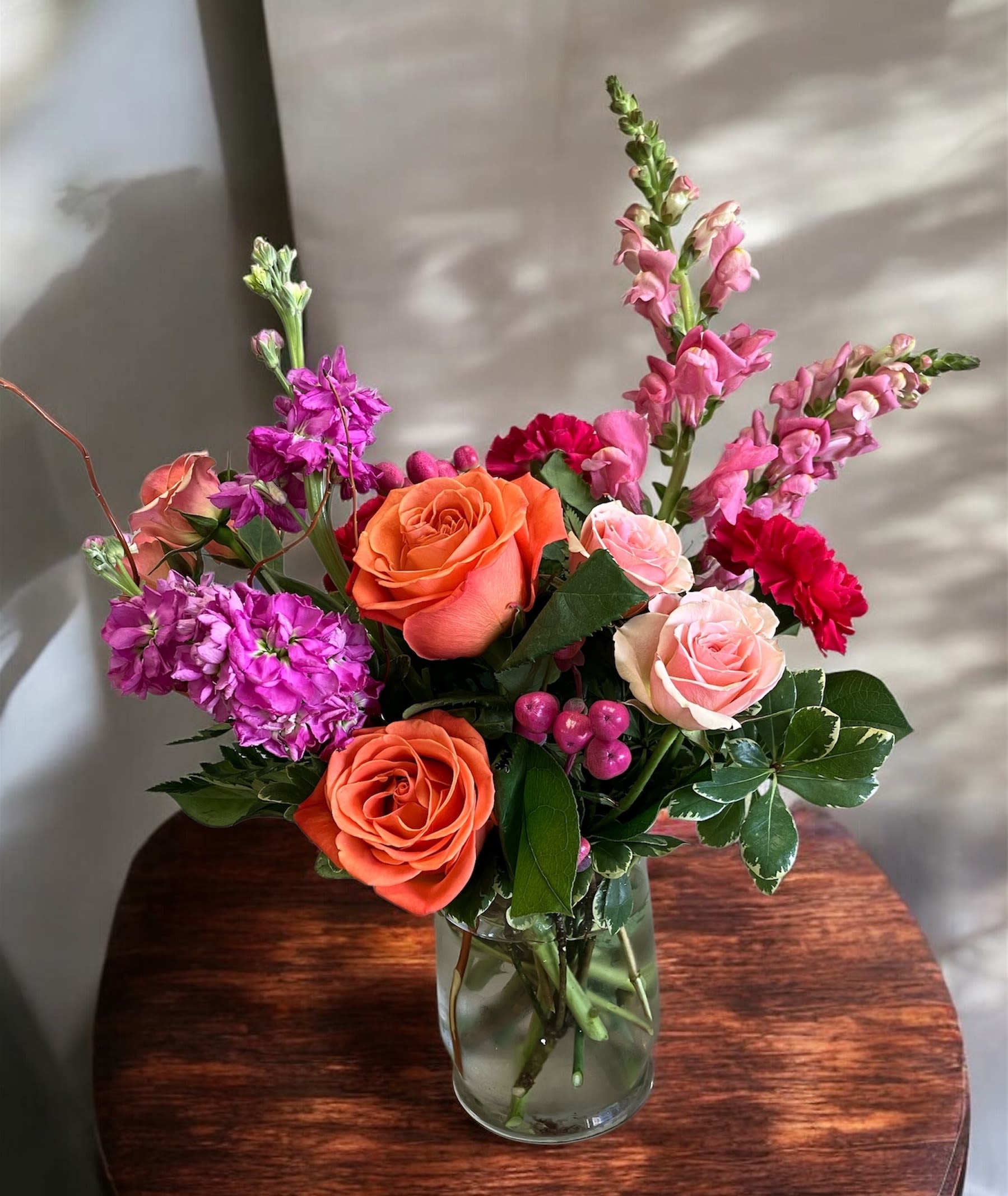 Happy Day - Bright and a little bit romantic, this flower arrangement is a joyful pick-me-up for birthdays, anniversaries, or simply to say thank you. The upright, full design features pink and orange roses alongside magenta carnations and pale pink snapdragons, creating a lively color story that reads both festive and intimate - the kind of bouquet that makes the person you're thinking of feel seen and celebrated.