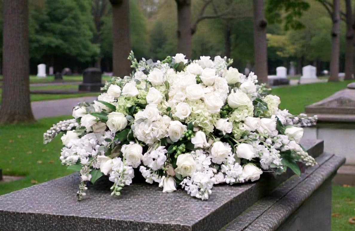 Serenity Casket Spray - White roses, hydrangeas and carnations with soft green accents arranged in a formal mound for a serene sympathy tribute on a casket or grave marker.