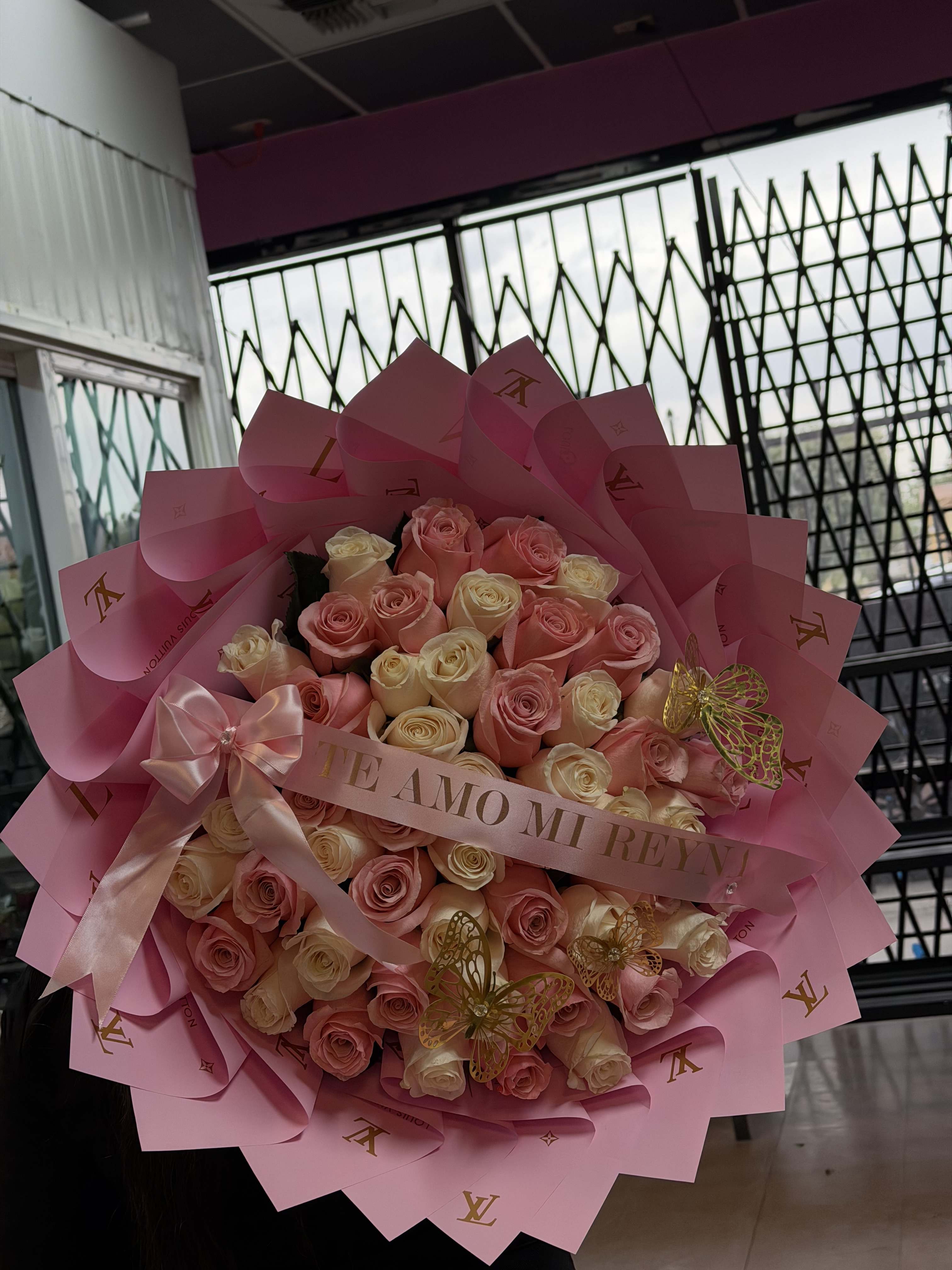 Pink and cream rose bouquet wrapped in pink paper with a ribbon