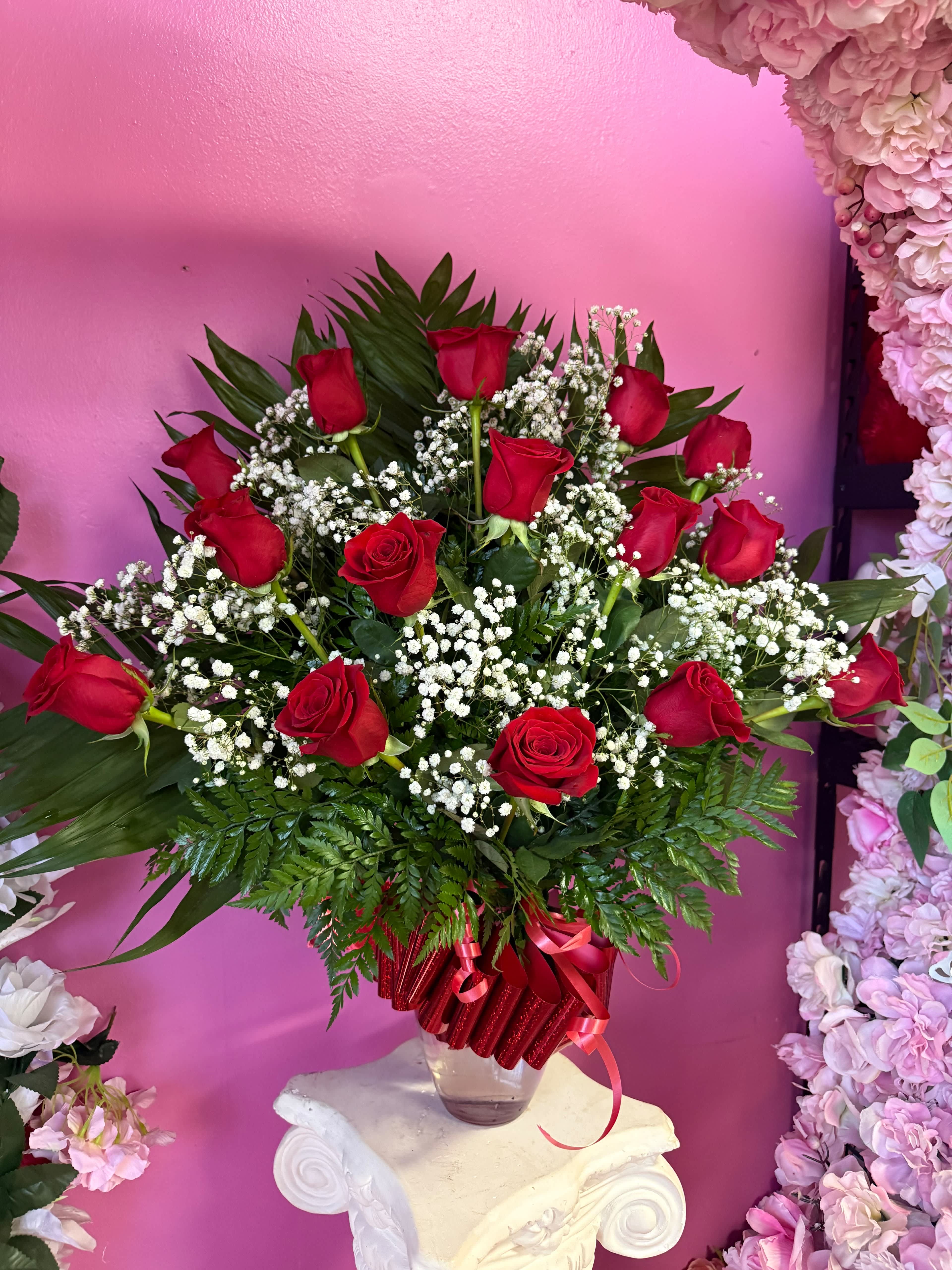 Red roses arranged in a clear vase with white baby's breath