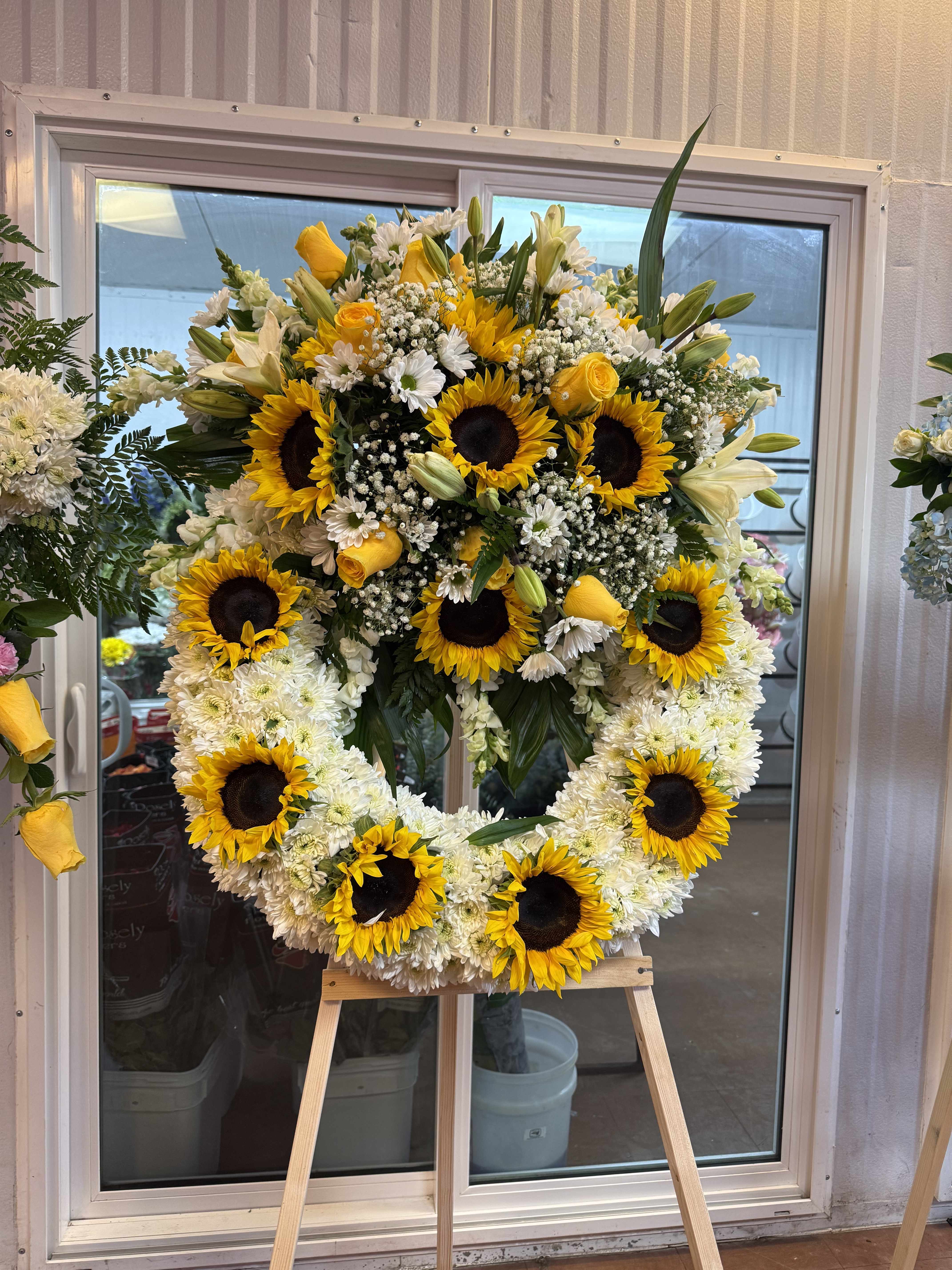 Large sunflower and white flower wreath on an easel