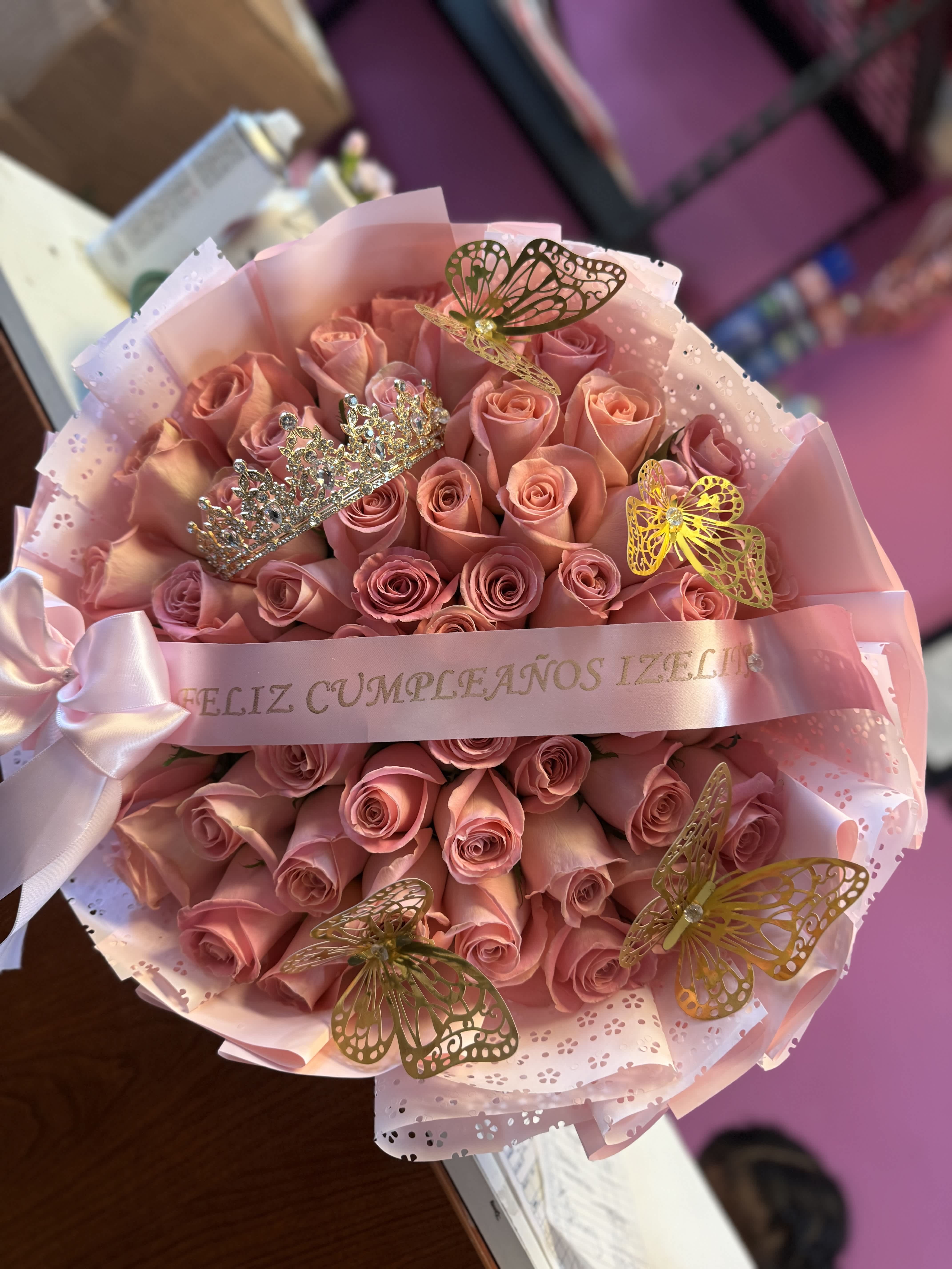 Bouquet of pink roses wrapped in pink paper with butterfly decorations