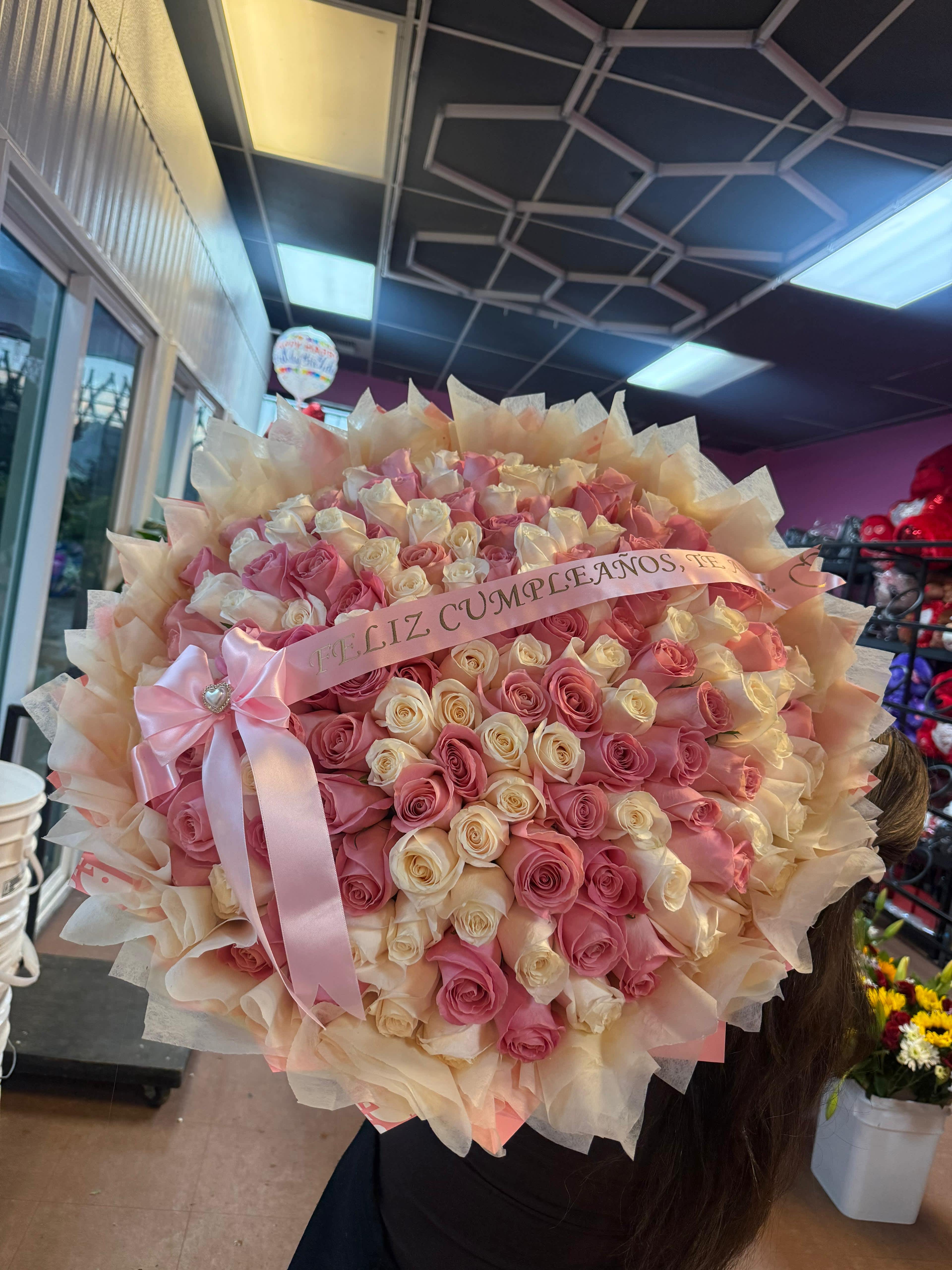 Large bouquet of pink and cream roses with a pink ribbon