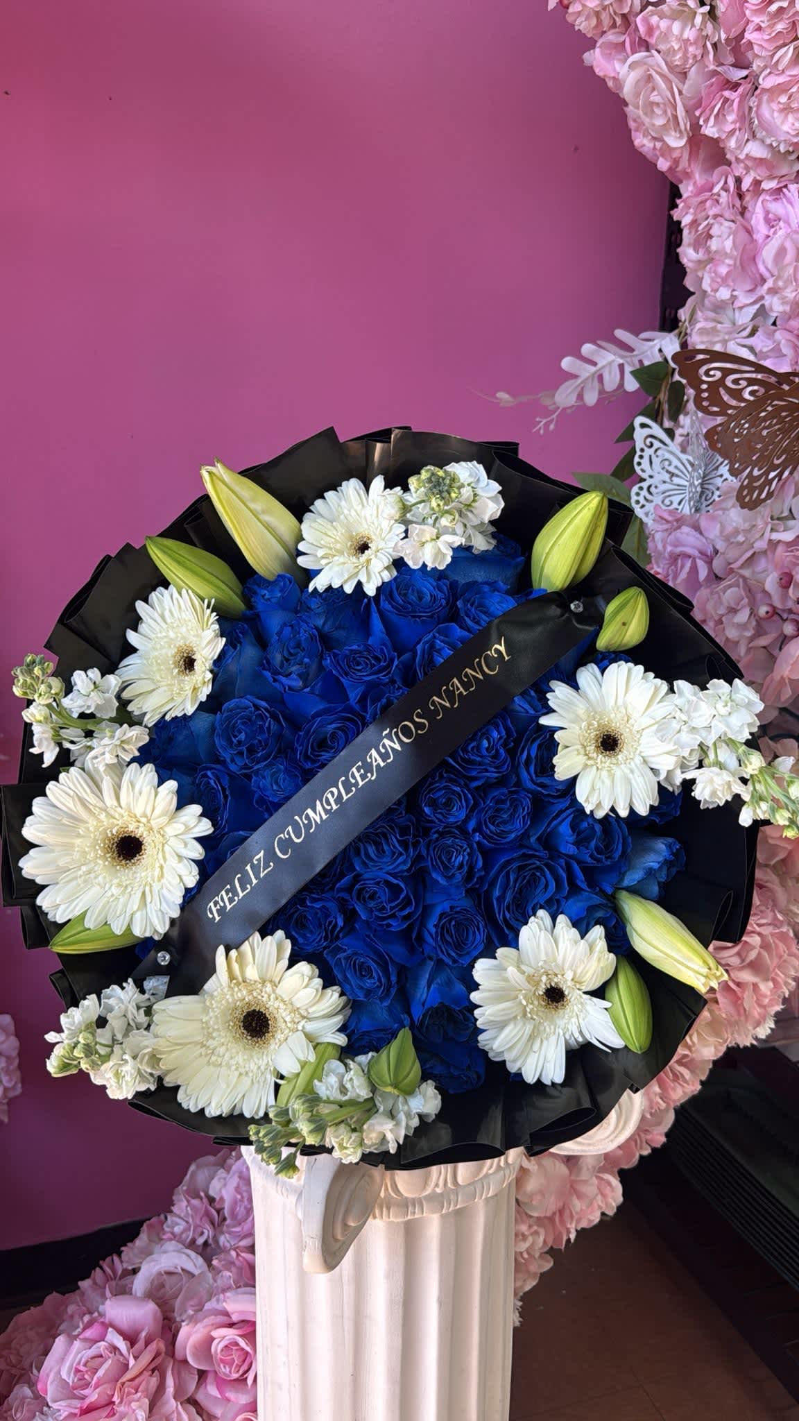 Blue rose bouquet with white daisies and lily buds in black wrap