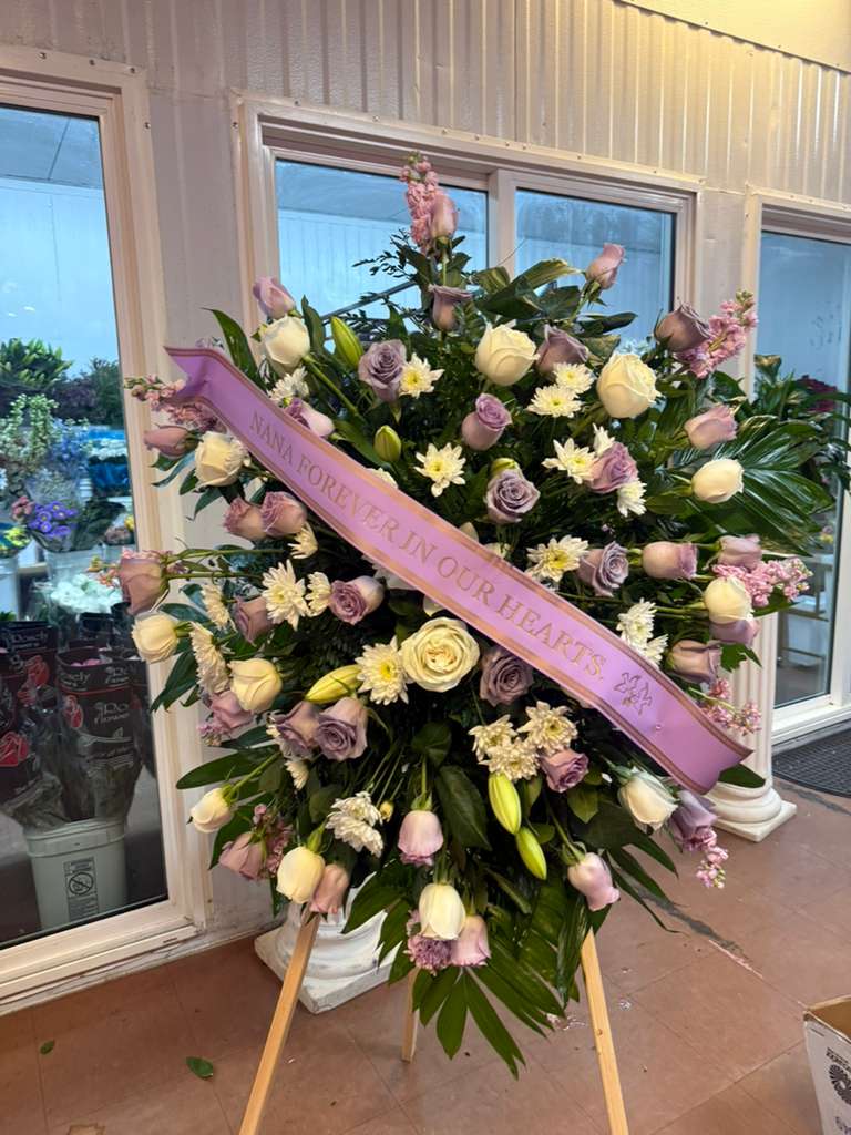 Large standing floral spray with a pink memorial ribbon