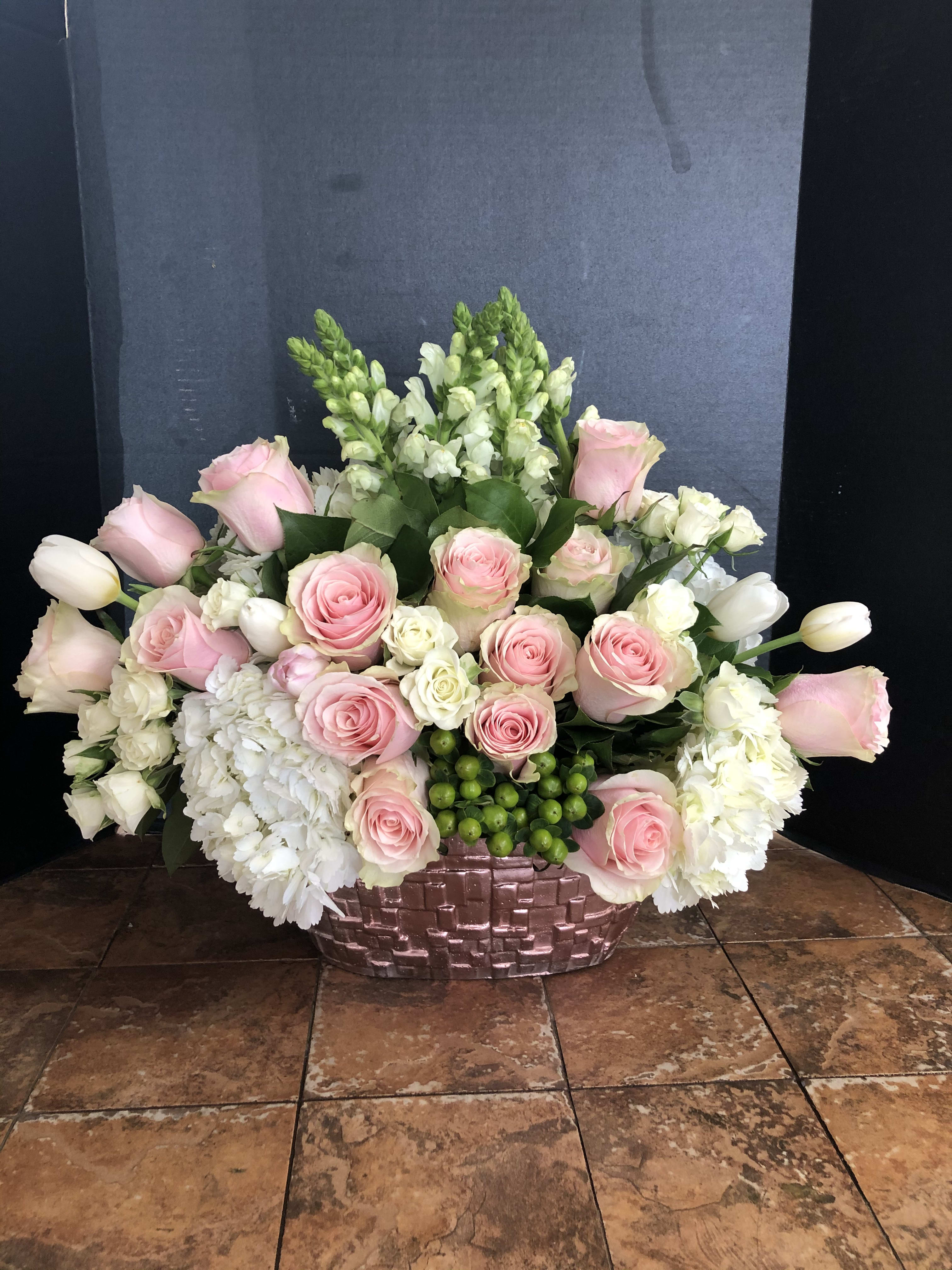Pink roses and white flowers arranged in a woven basket