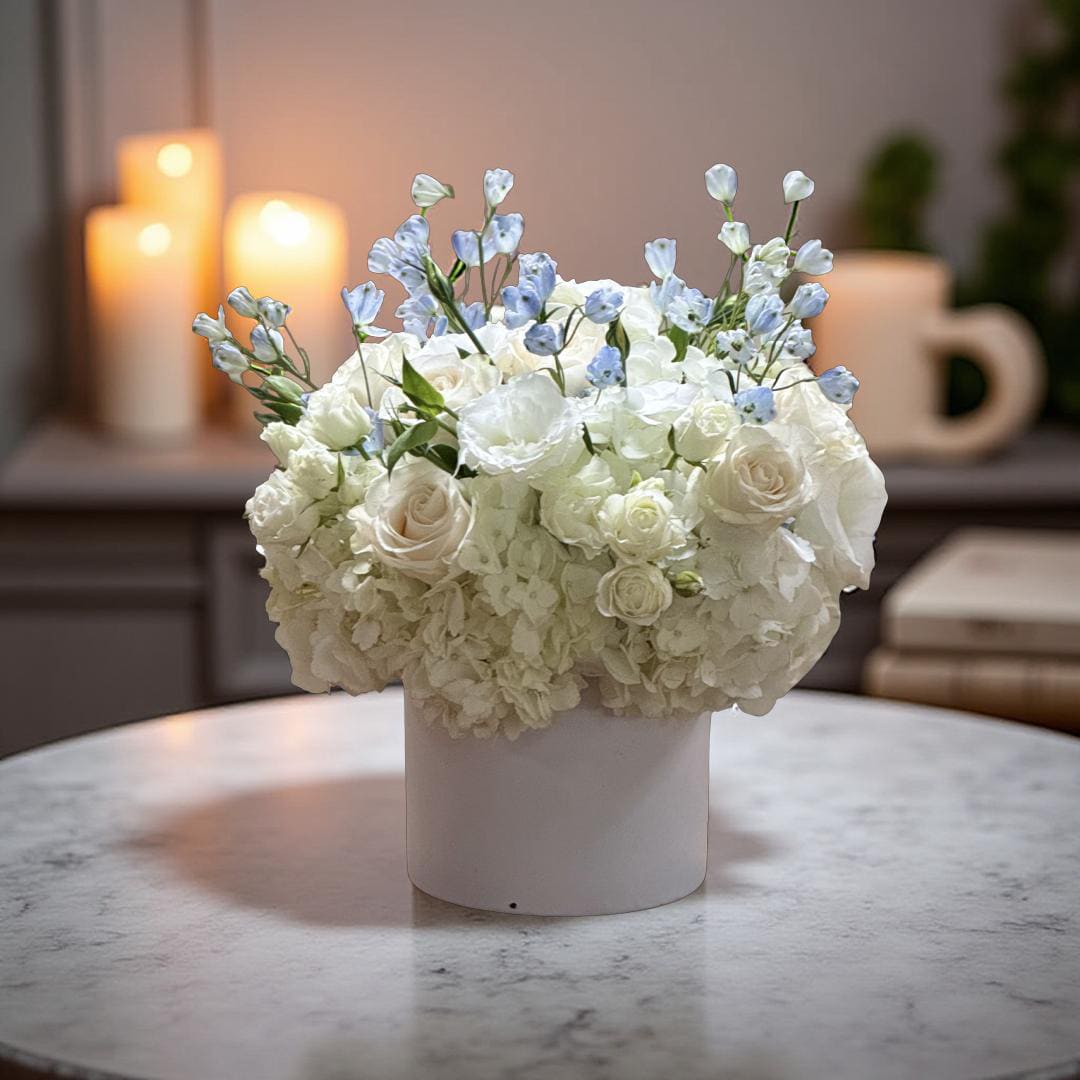 White roses and hydrangeas in a white vase with pale blue accents
