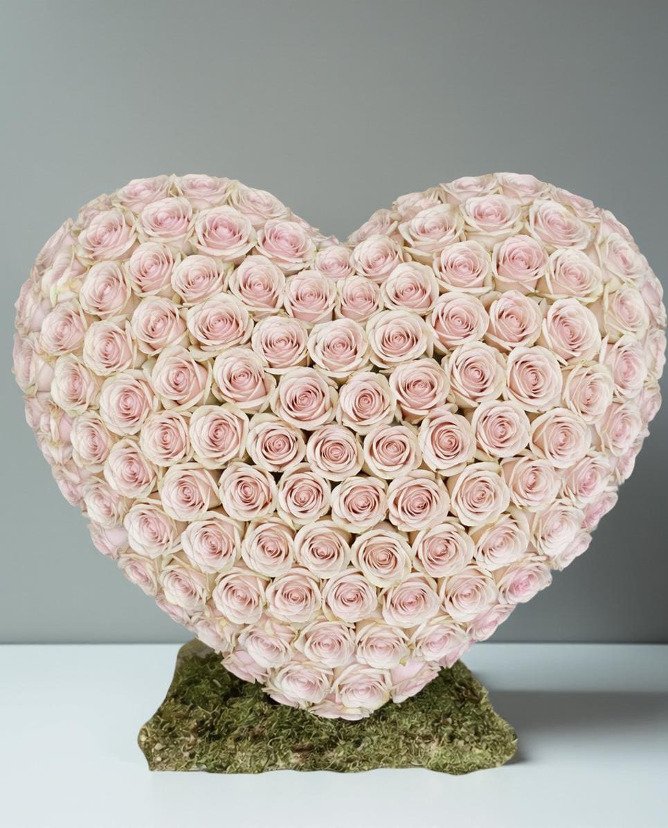 Heart-shaped arrangement of pale pink roses on a moss base