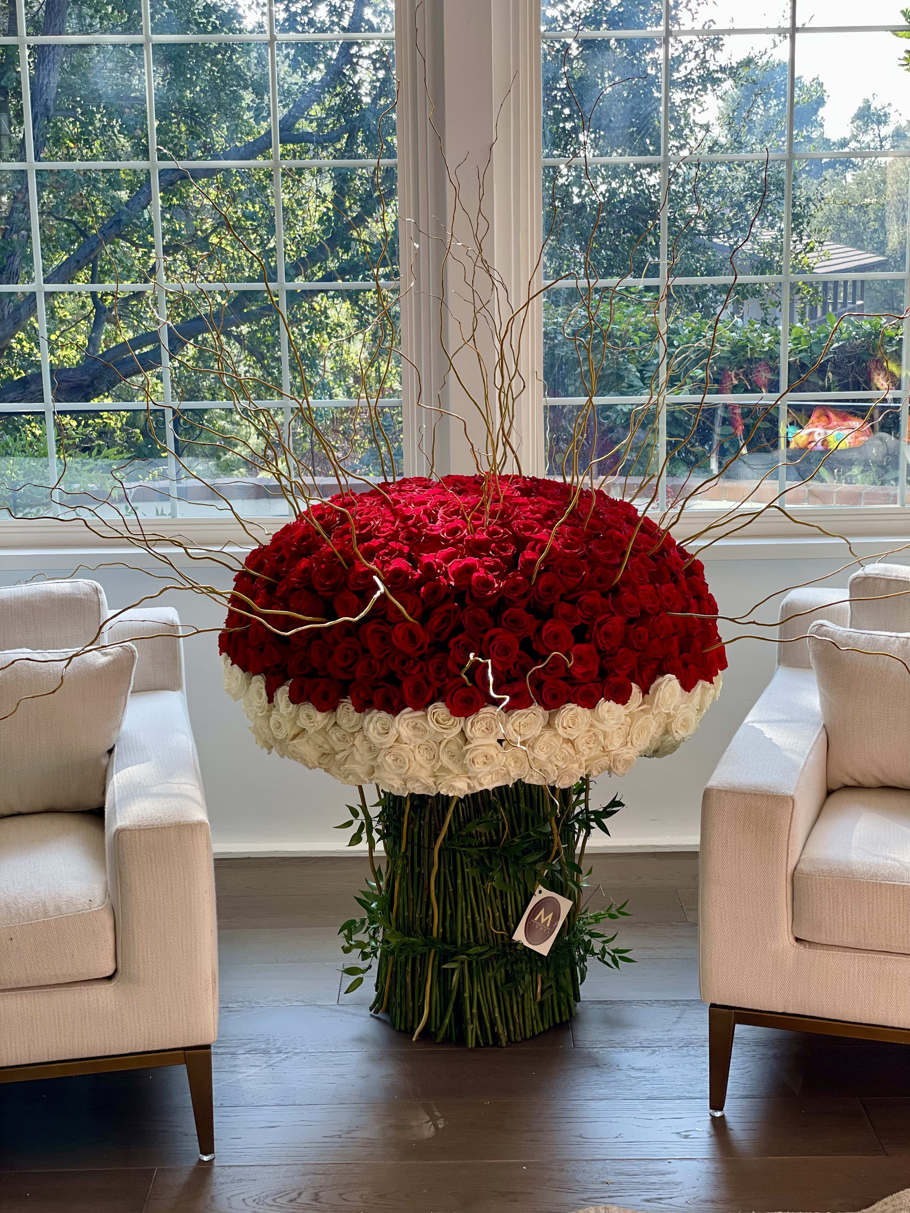 Large red and white rose arrangement with tall curly branches