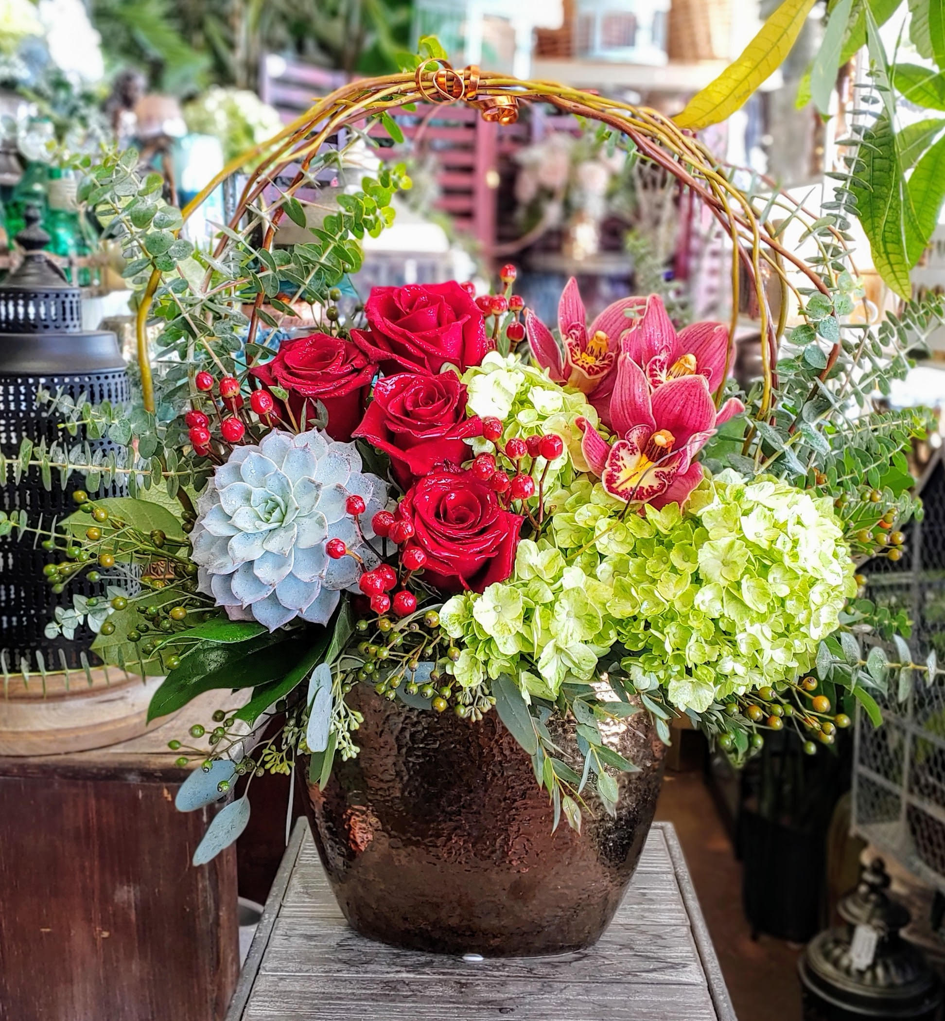 Red roses and pink orchids in a dark vase with a woven handle