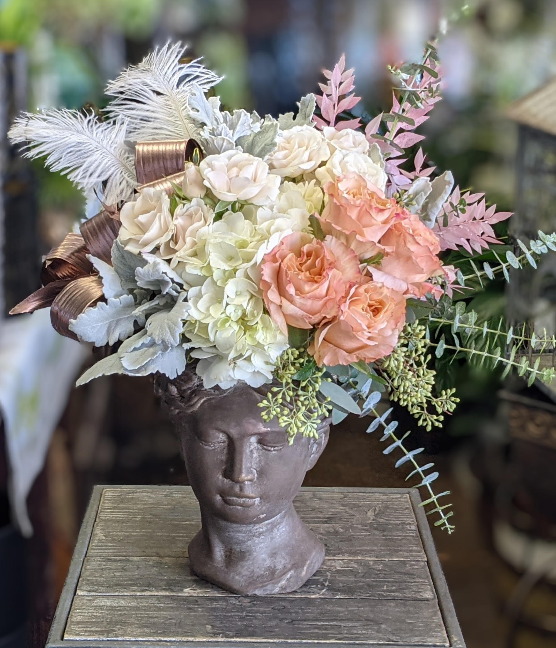 Floral arrangement in a sculpted head vase with cream and peach blooms