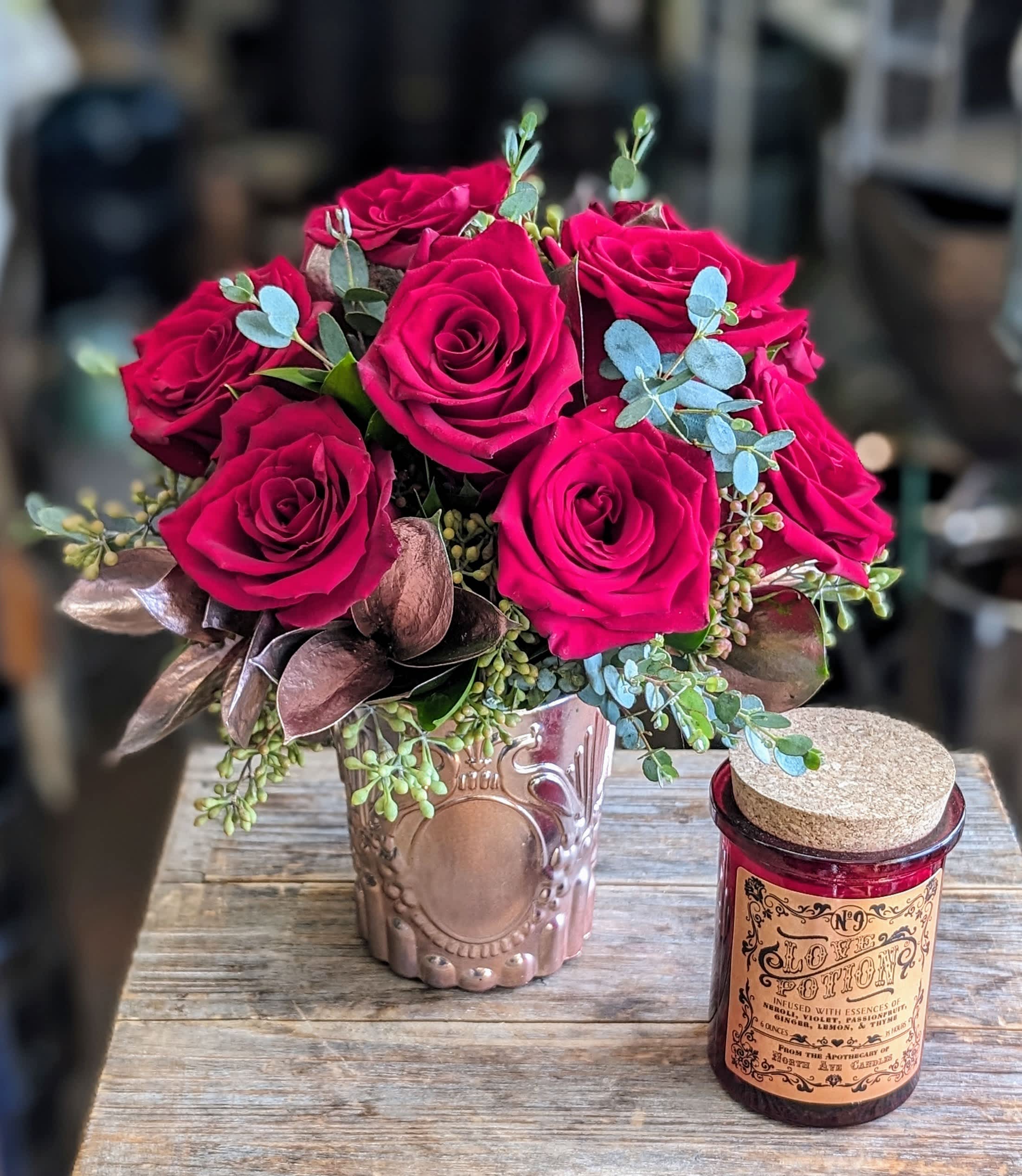 Bouquet of hot pink roses in a decorative vase beside a candle jar