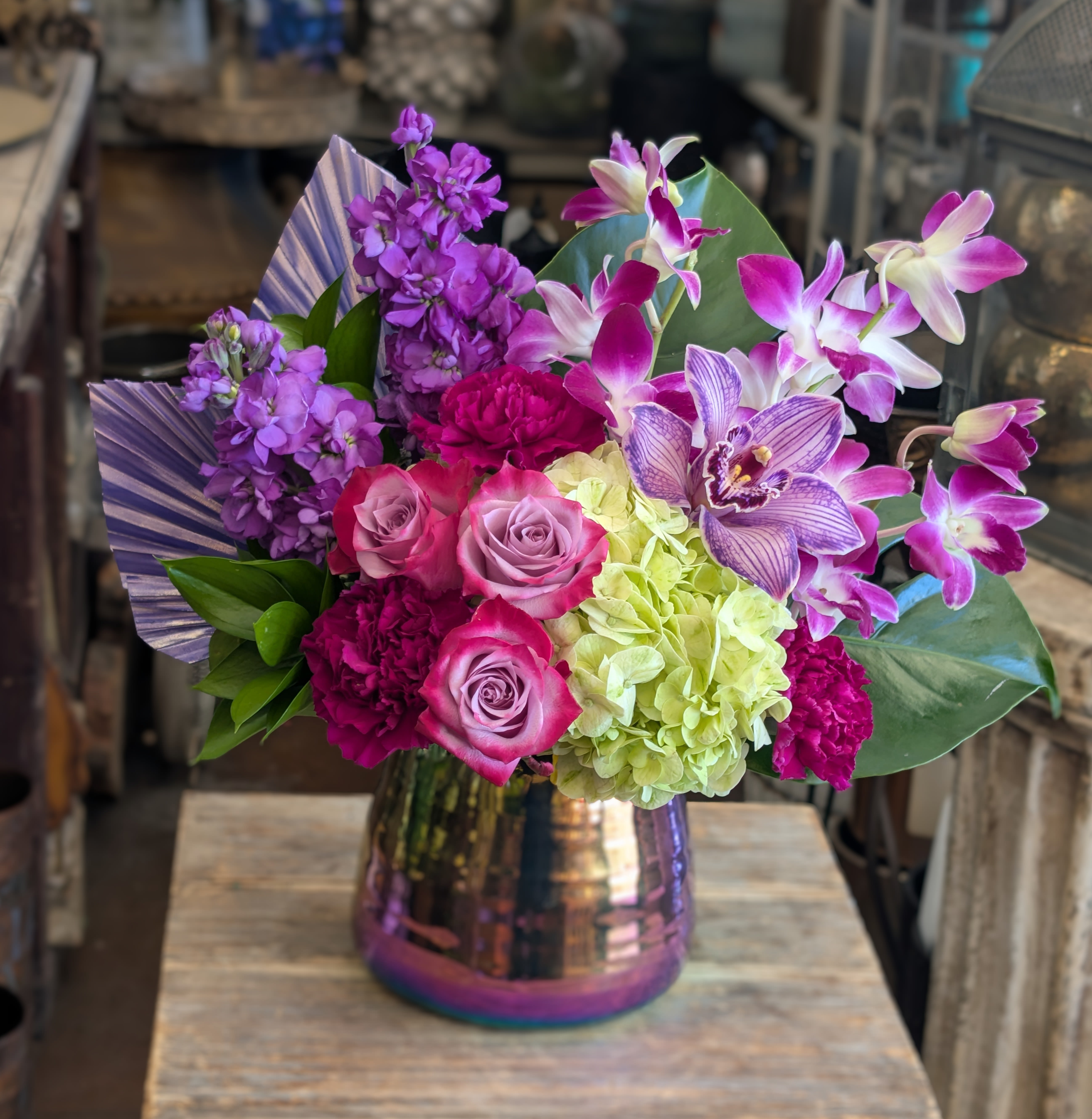 Bouquet of purple orchids, roses, and hydrangea in a metallic vase