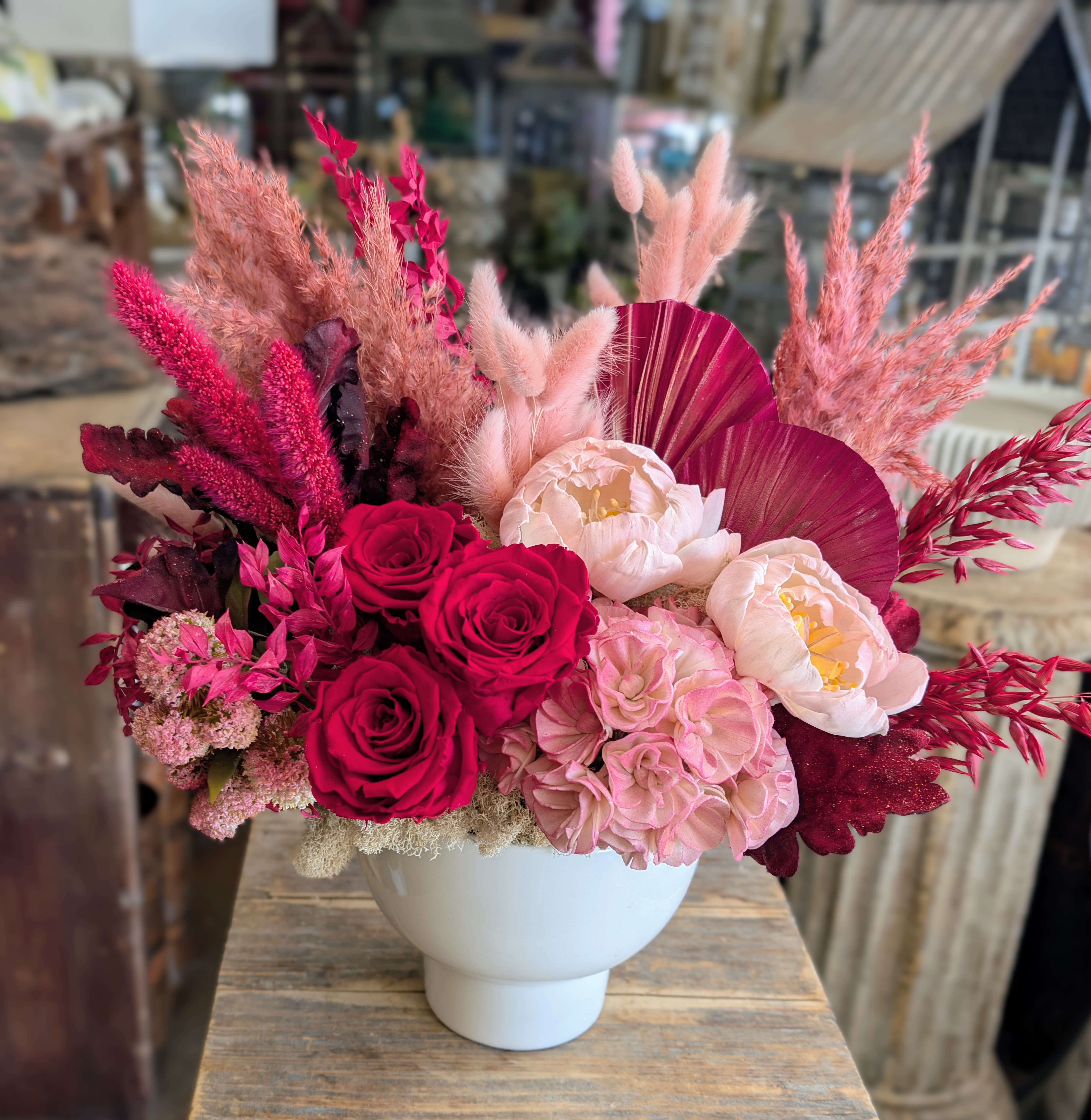 Pink and burgundy floral arrangement in a white vase