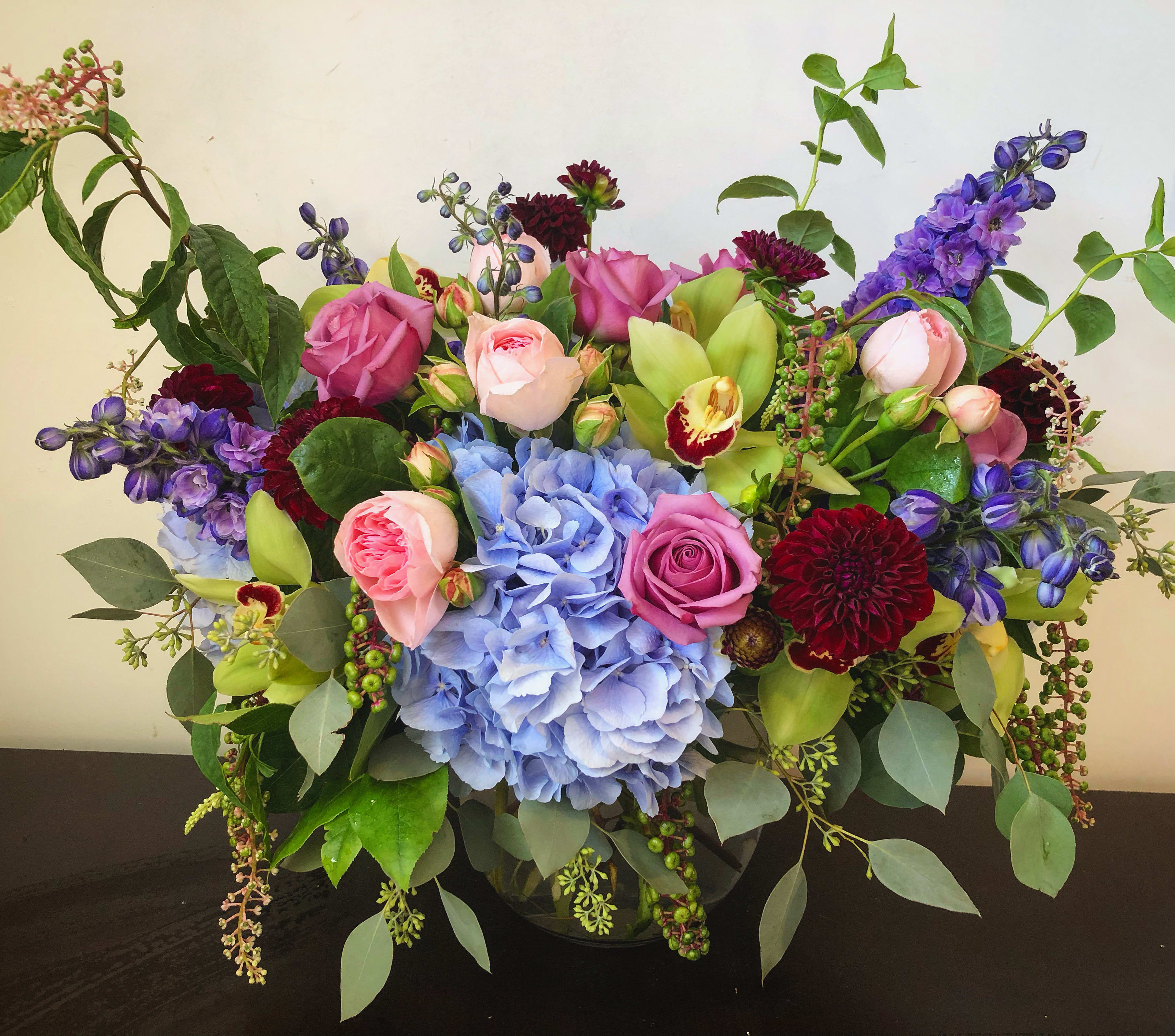 Mixed bouquet with pink roses, blue hydrangea, and purple flowers in a vase