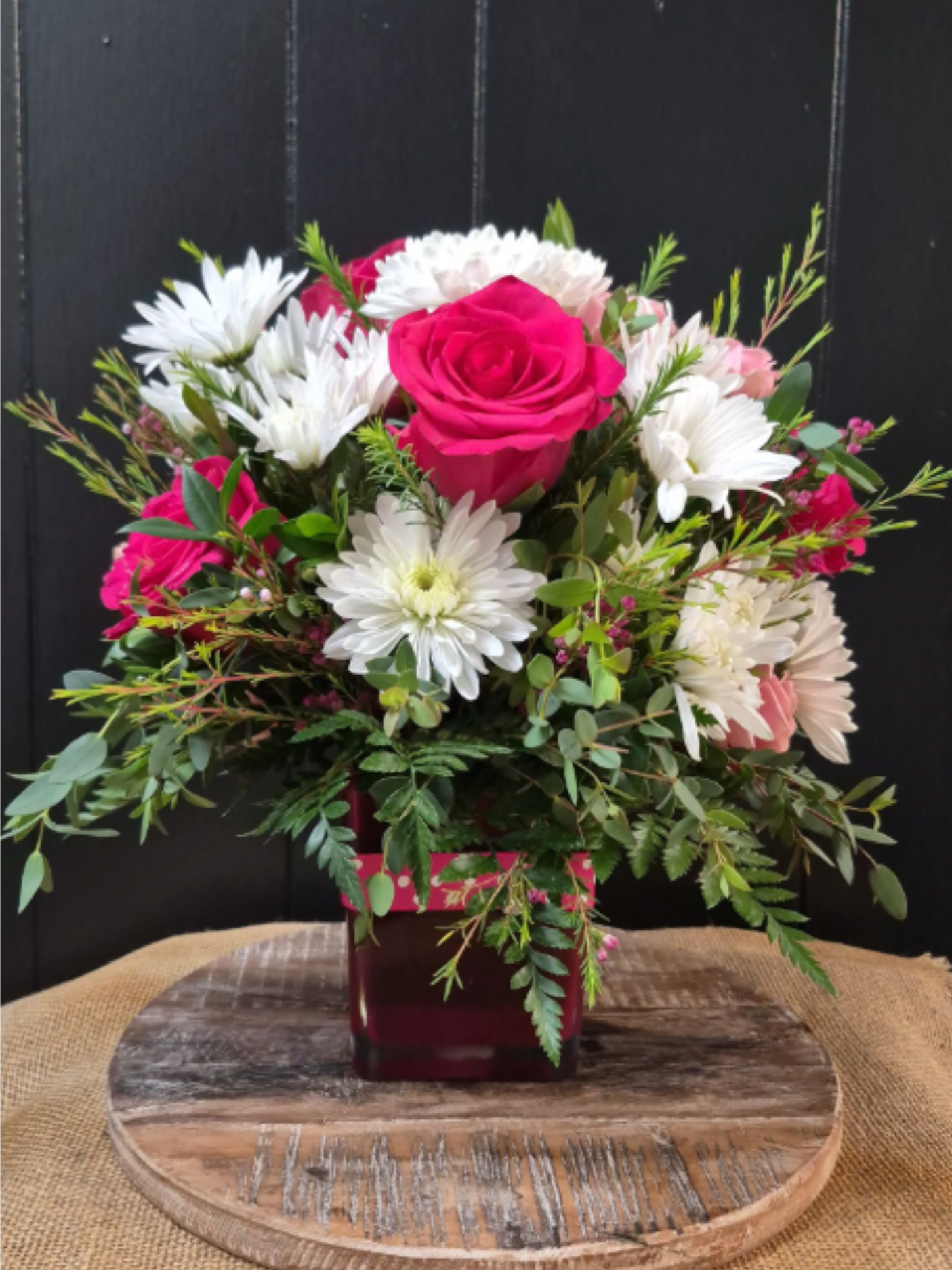 Pink Polka Dot - Hot pink roses, spray roses, and white daisies in a pink vase with a polka dot ribbon