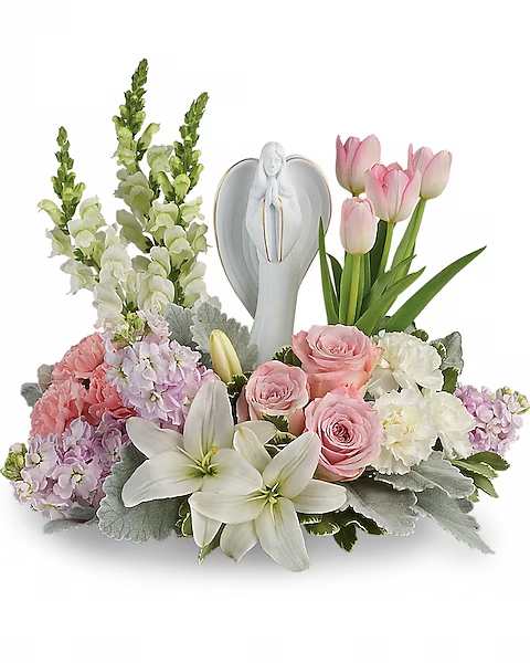 Pink tulips, roses, lilies, and snapdragons arranged around an angel figurine