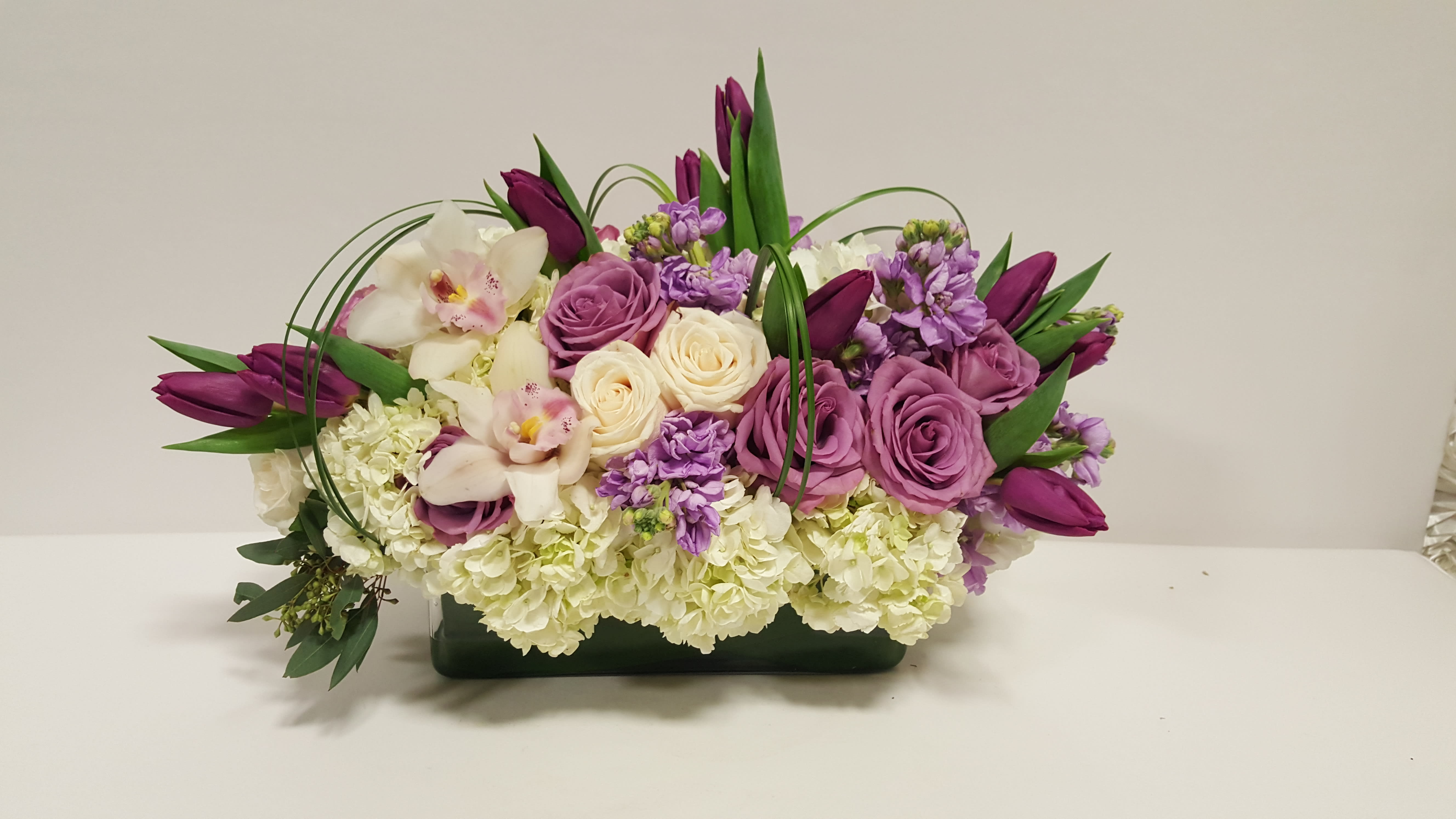 It’ll bring a smile to their face - rectangular glass vase 12X5X5 with a lovely combination of lavender and ivory flowers