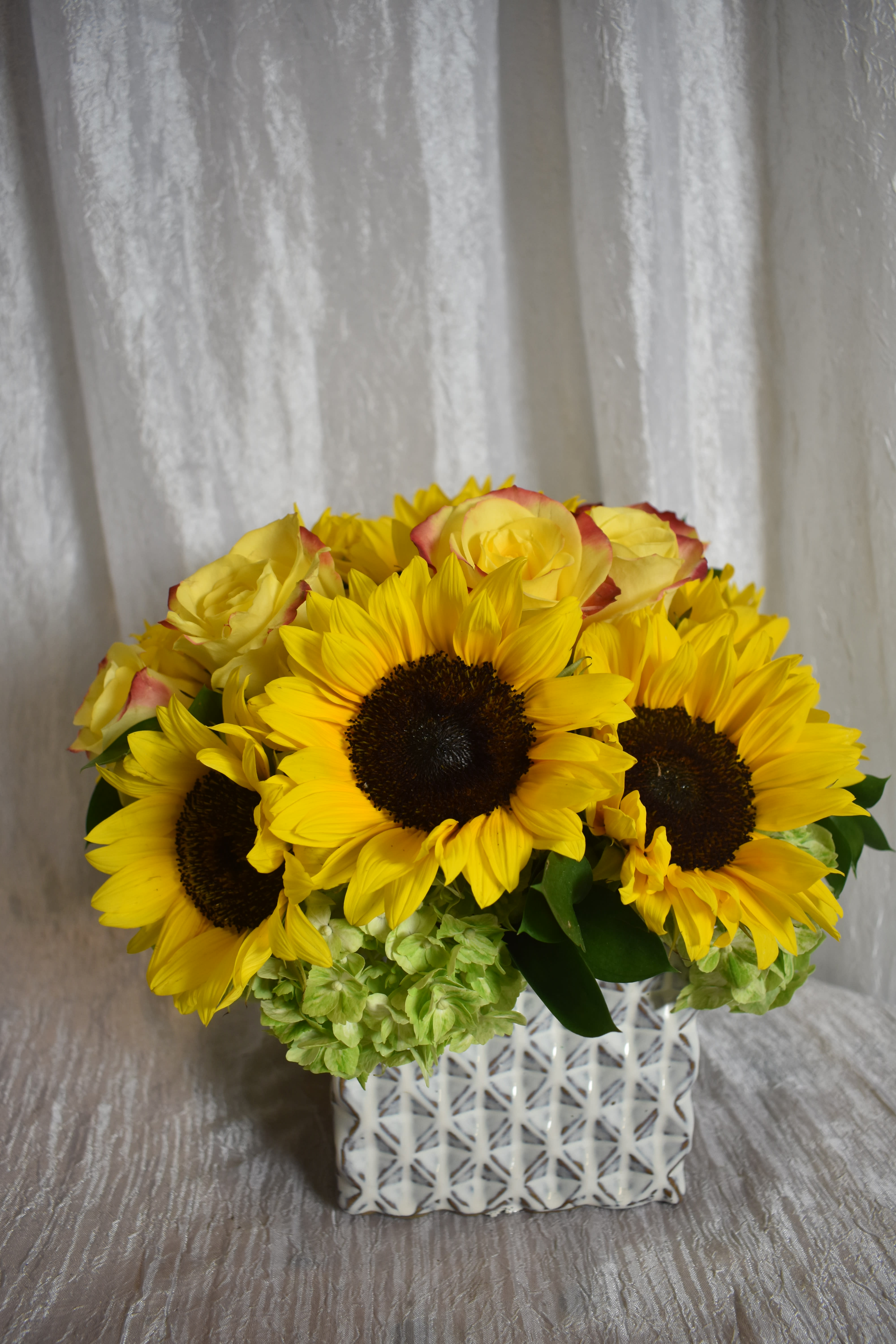 sunflower mix  - a square vase  with sunflowers and yellow roses with a touch of green hydrangeas 