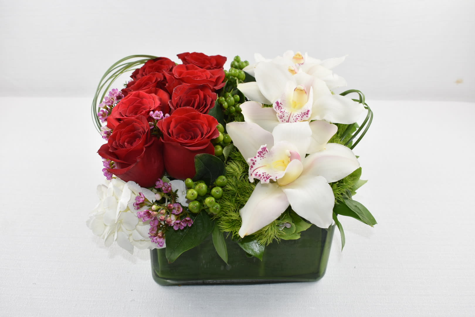 Fancy-Sebas Flowers Design  - A unique Sebas Flowers design  In a low square vase  with 2 different lovely sides that compliment each other  on one side it contains some beautiful Ecuadorian red roses and on the other side it has some lovely cymbidium orchids and together they create a fancy floral arrangement  Perfect gift for any occasion  Perfect for  birthday flowers anniversary flower  just because flowers  congratulations flowers  Get well flowers  Christmas flowers Valentines Day flowers Mother's Day flowers  