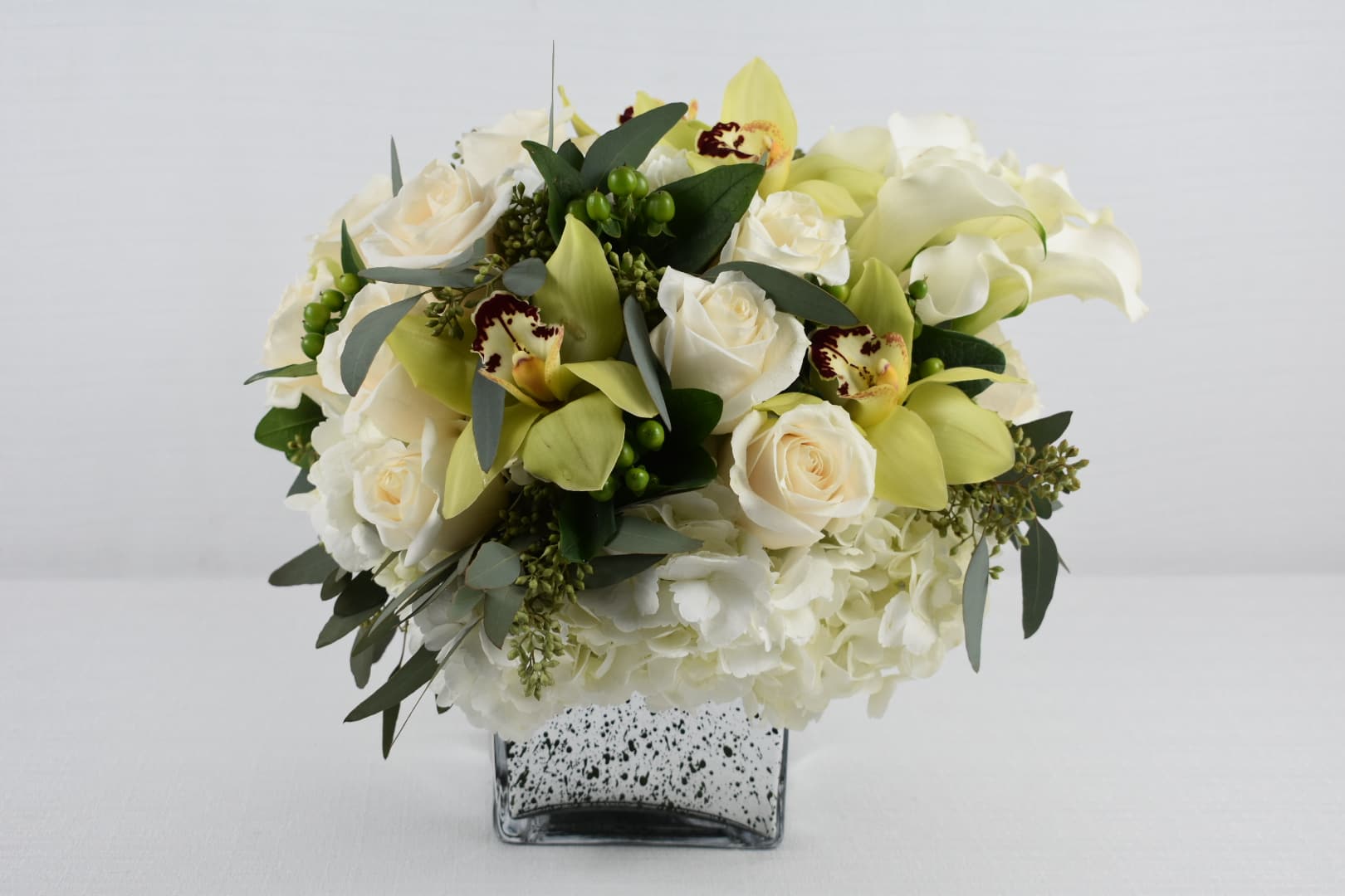 white and green  - silver square vase  with some fresh cut white roses combined with white hydrangeas and some greens 