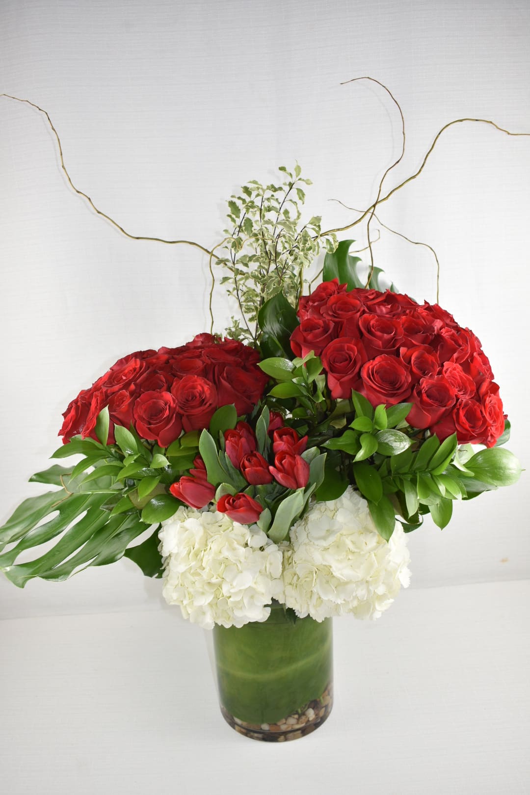 Chic Design - Sebas Flowers  - This grand Sebas flowers custom design  was created in a cylinder vase with a height of 7X12  contains 50 Ecuadorian Red roses (long stem) with an extraordinary greenery and to complete the perfect look it has white hydrangeas and red tulips  She will definetly love this design  Perfect for  birthday flowers anniversary flower  just because flowers  congratulations flowers  Get well flowers  Christmas flowers Valentines Day flowers Mother's Day flowers  