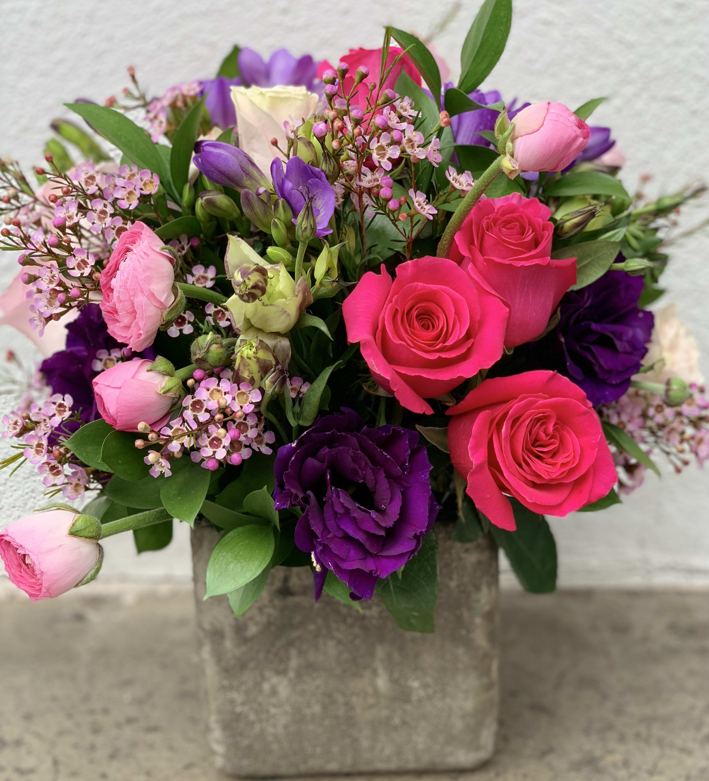 Spring Purple and pink  - Rustic square vase  with a beautiful color combination of purple and pink  This lovely arrangement has Ecuadorian pink roses, purple Freesia, purple licianthus, pink Ranunculus, purple wax and some beautiful greens as accents  The perfect size for an office desk 