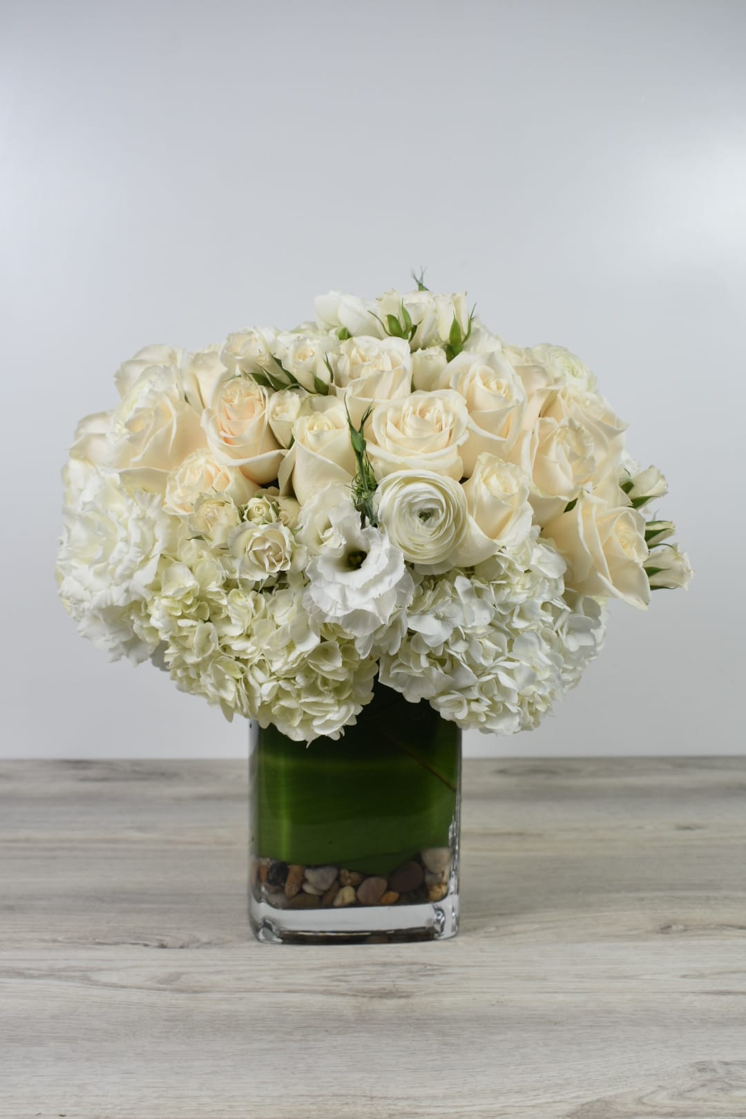 White rose and hydrangea arrangement in a square glass vase